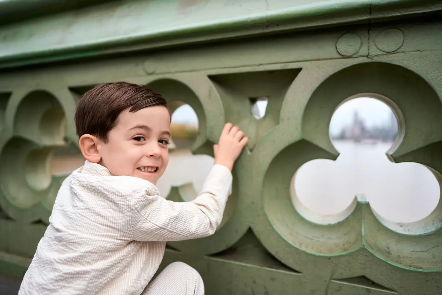 Toddler boy looking through Westminster Bridge's stone balustrade, London