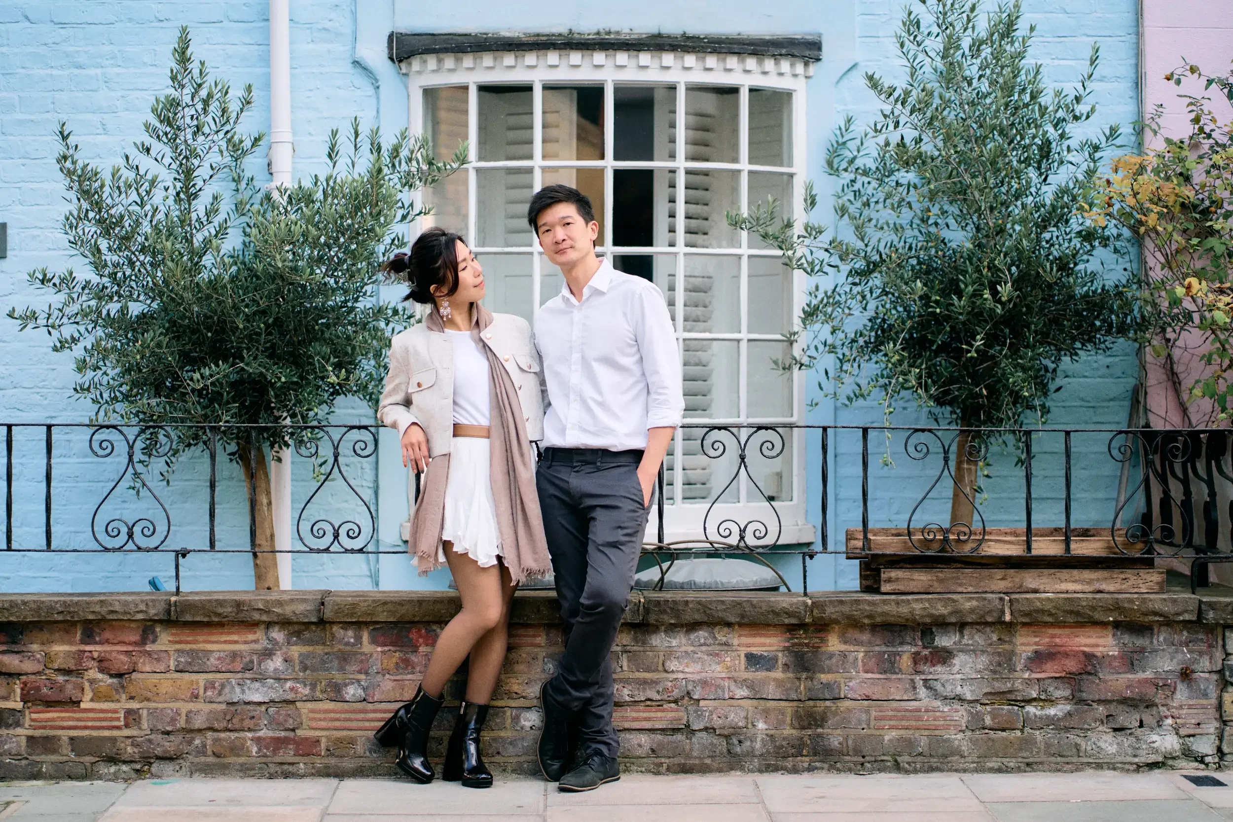 Couple standing against a baby blue painted house with olive trees and wrought iron railings in Notting Hill, London - Tepewehco Photography by Kate