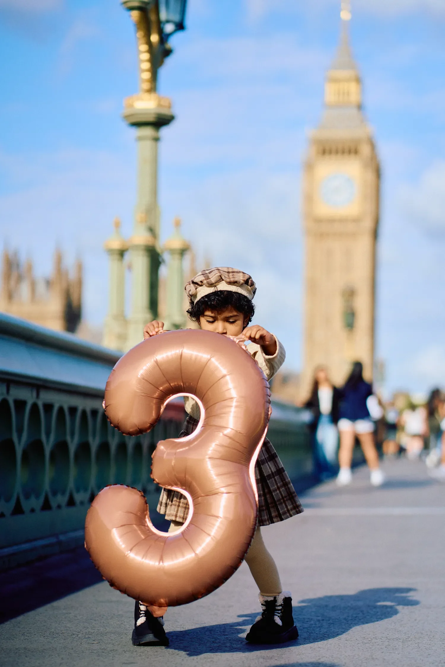 Toddler holding a number three birthday balloon on Westminster Bridge