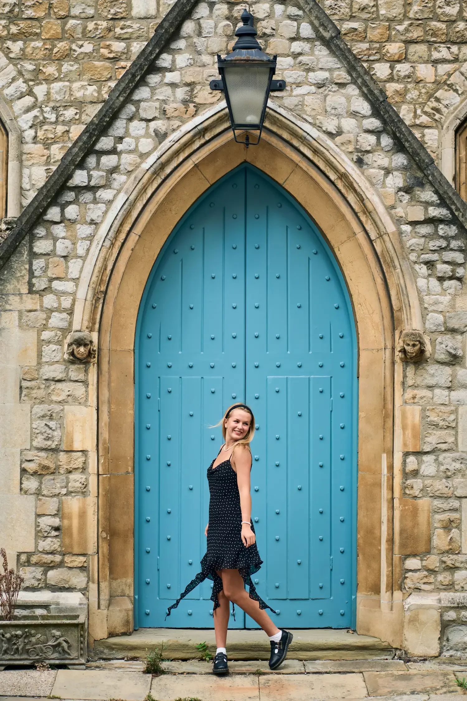 Woman in a black dress framed by a bright blue gothic doorway in Belgravia