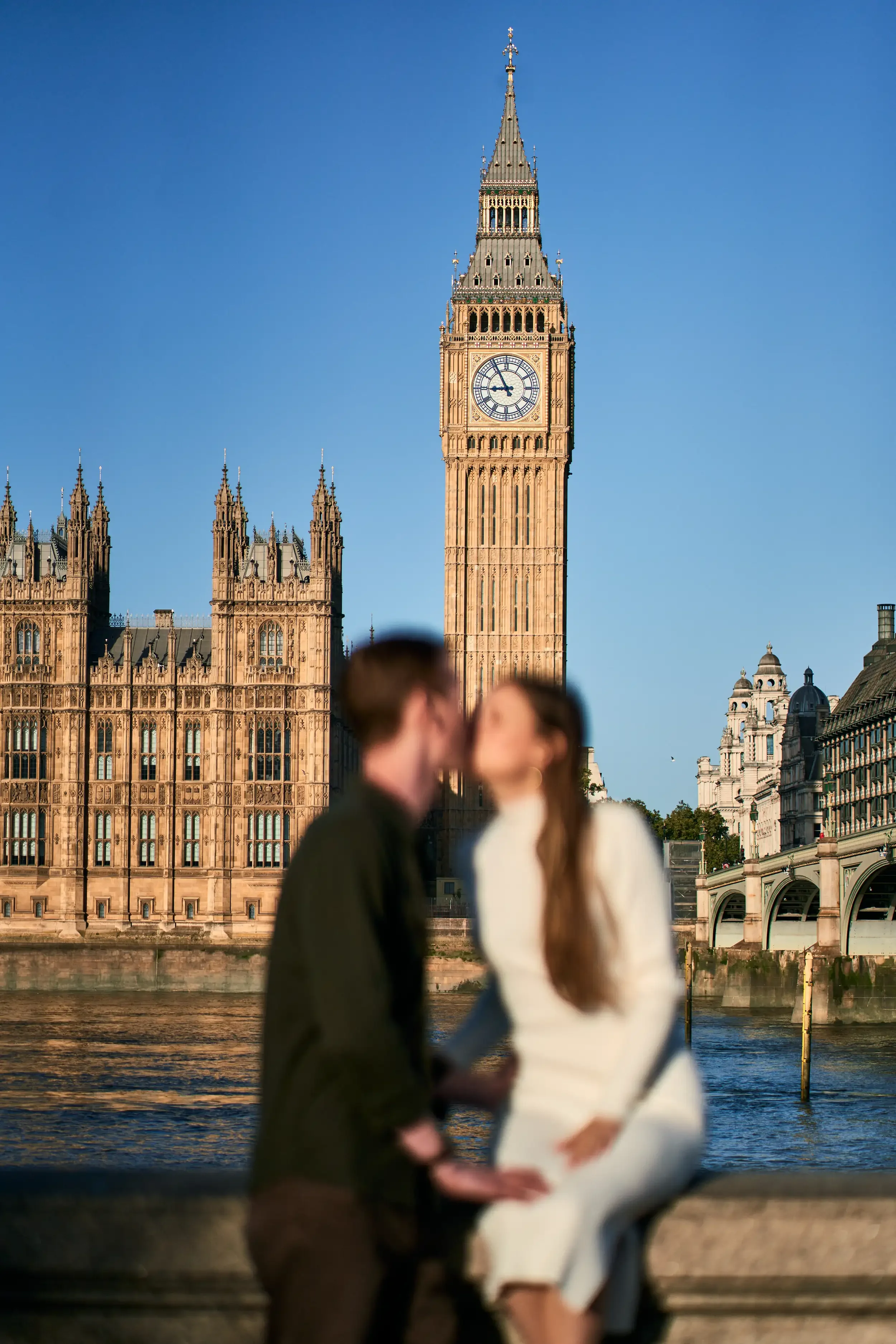Man kissing woman on the cheek as she smiles during a couples photoshoot on the South Bank near Westminster, London