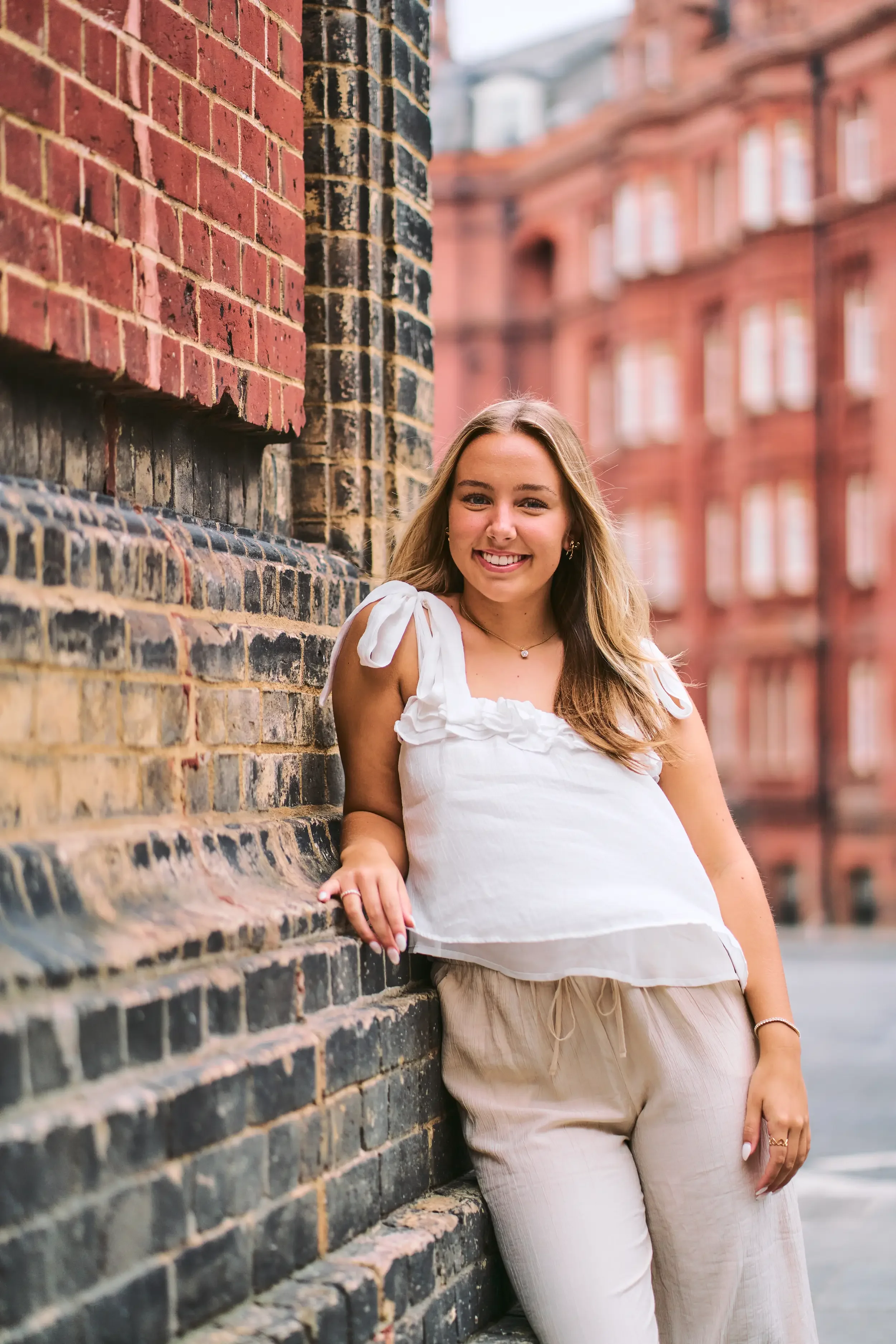 Smiling high school senior holding an iron railing with red brick Kensington apartments in the background, London