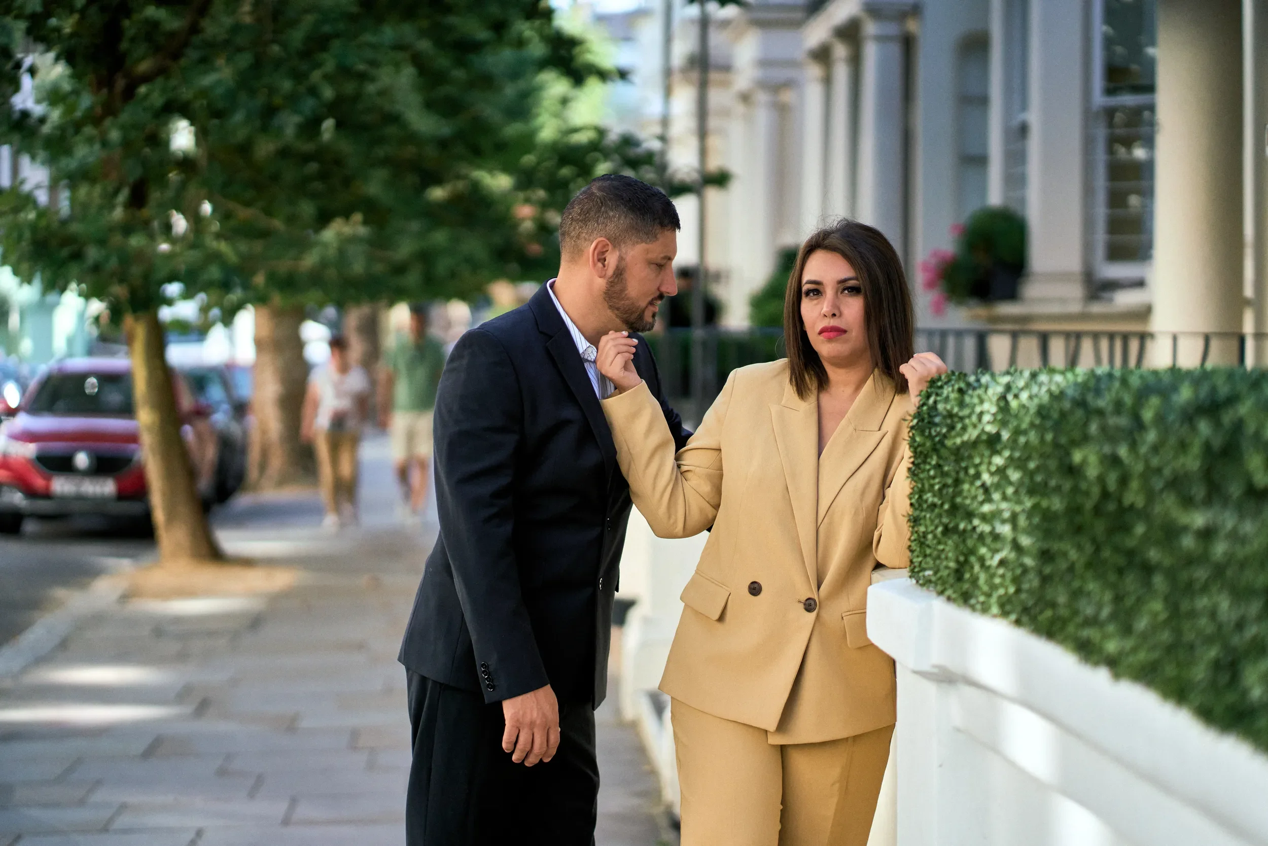 Couple in coordinating suits posing on a tree-lined London street — outfit inspiration for what to wear to a London photoshoot