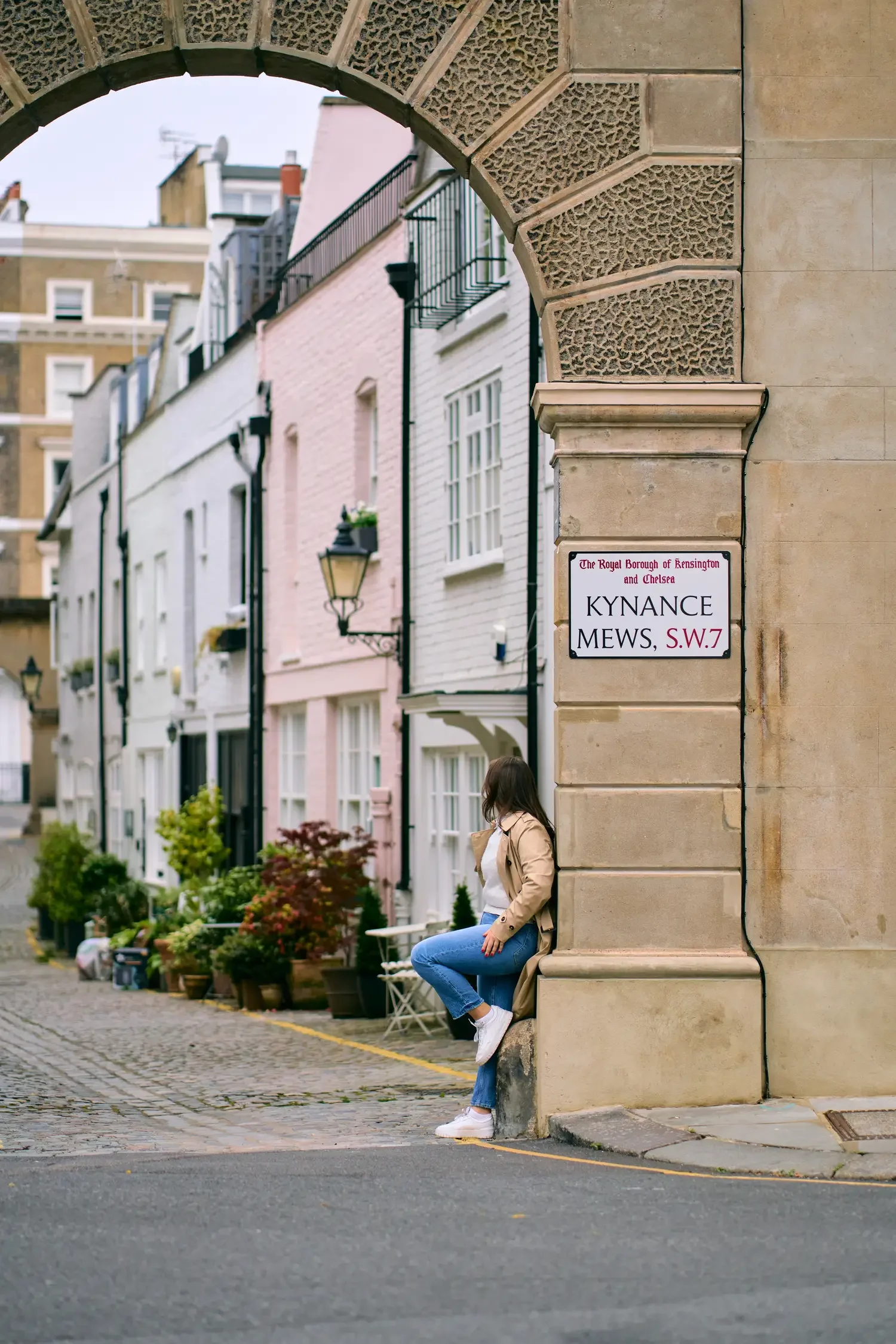 Woman in a white shirt and jeans sitting on a step in Kynance Mews, Kensington