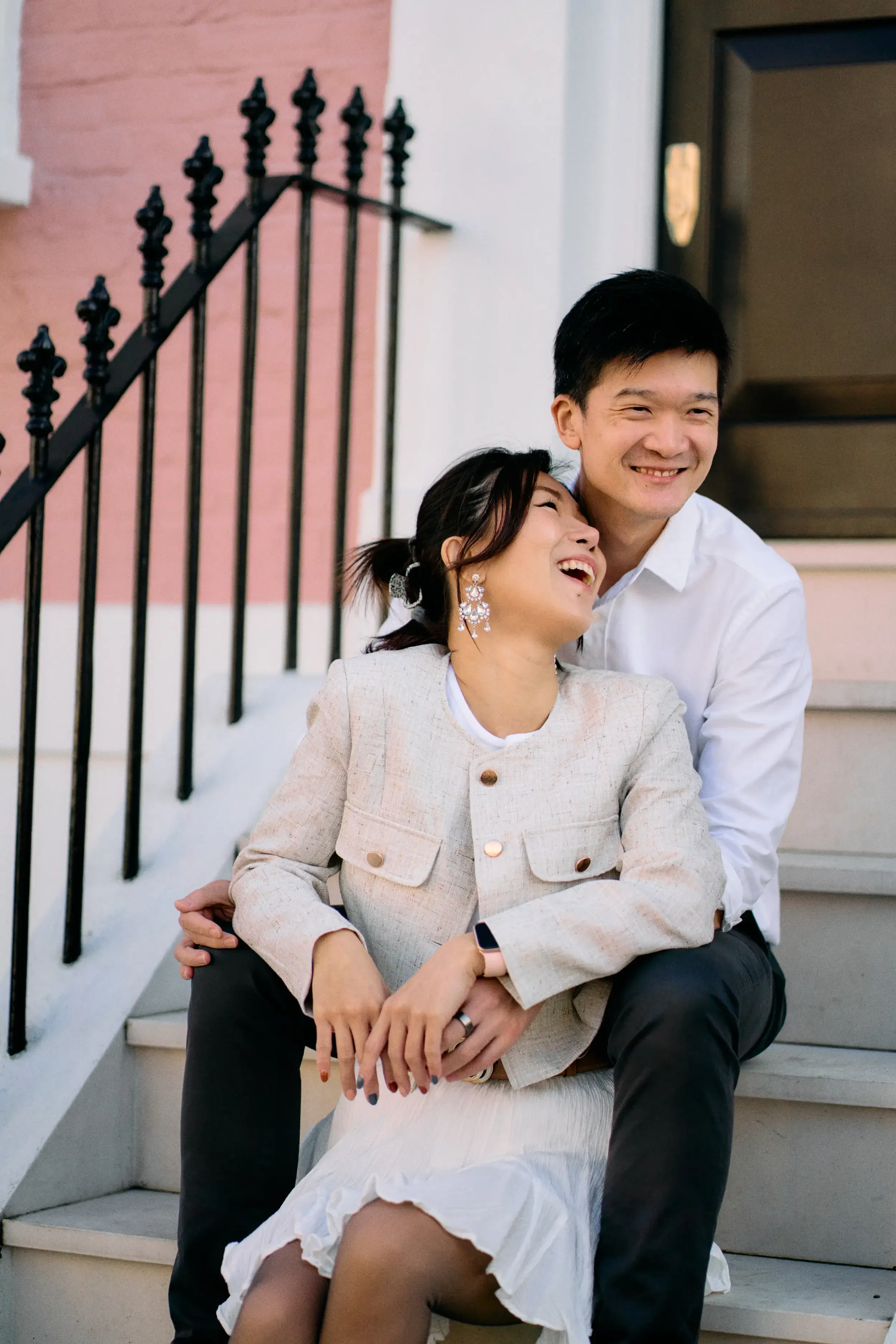 Couple laughing together sitting on the steps of a pink townhouse on Farmer Street, Notting Hill, London - Tepewehco photography by Kate