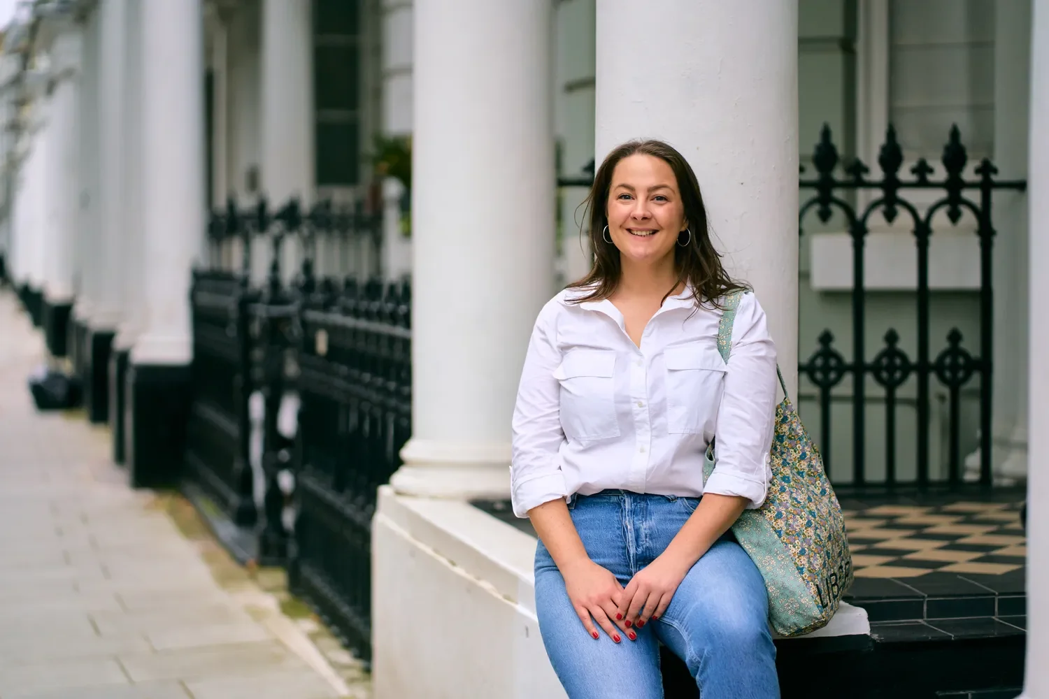 Personal brand portrait of a woman in a lilac shirt by black railings in Chelsea