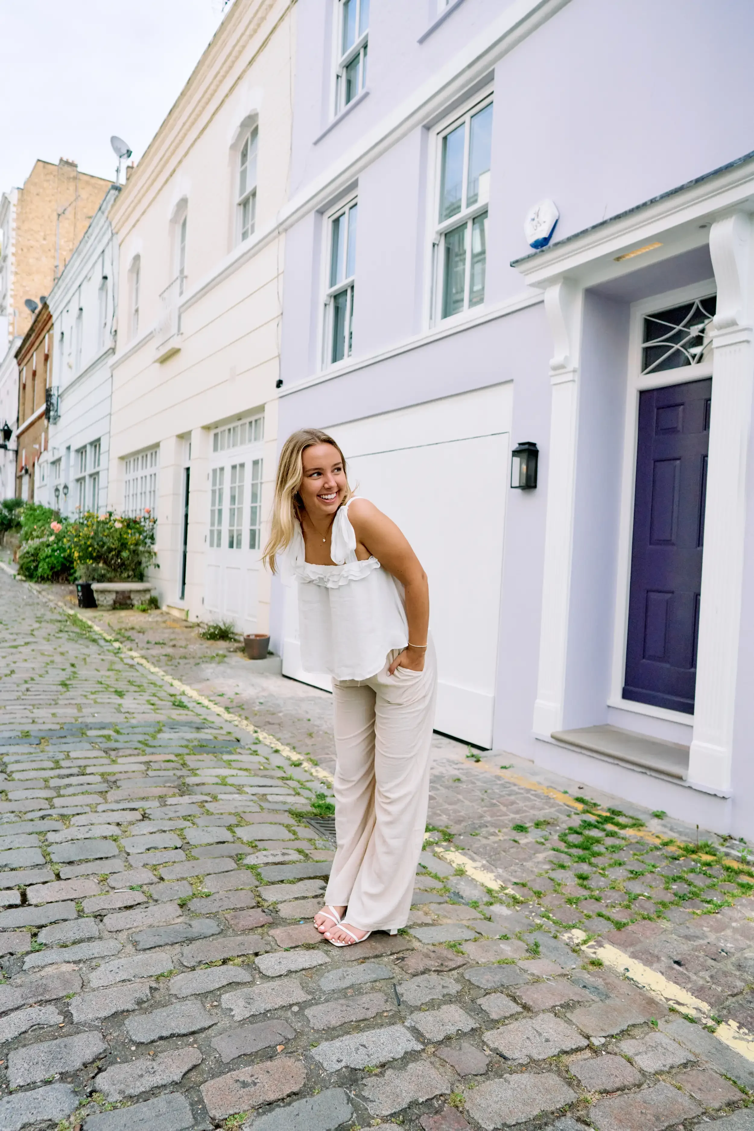 High school senior laughing on a pastel-coloured cobblestone mews in Kensington, London