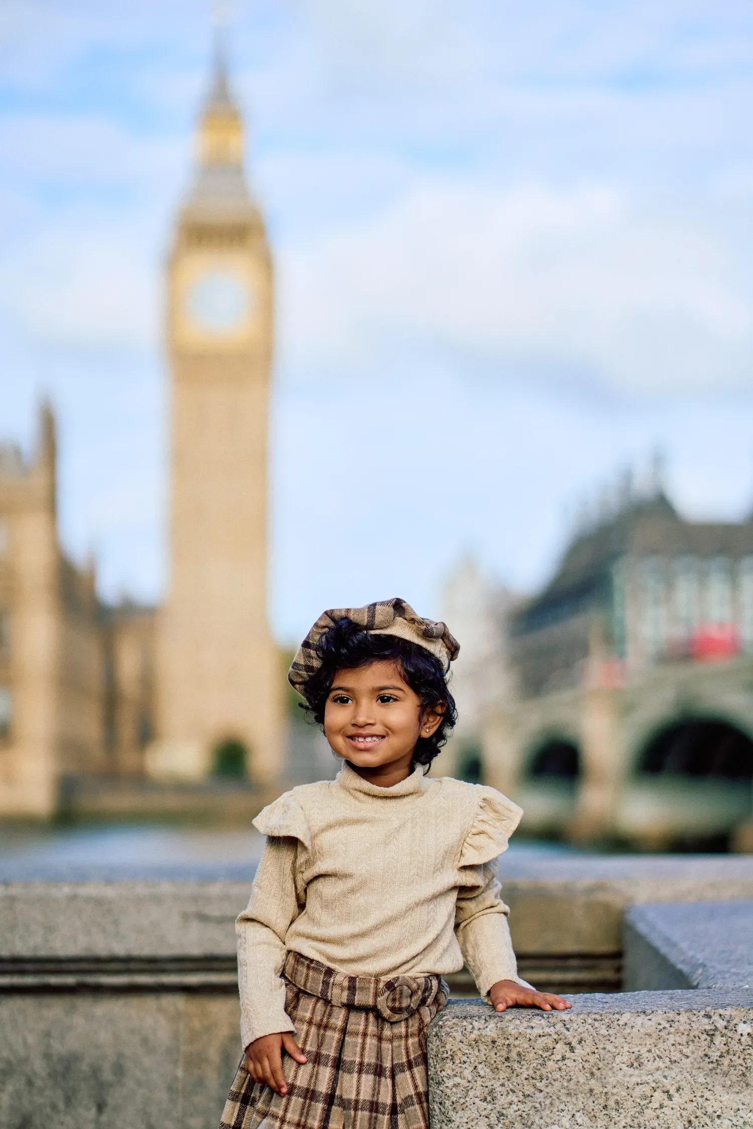 Young girl in a tartan skirt leaning on Westminster Bridge balustrade, London