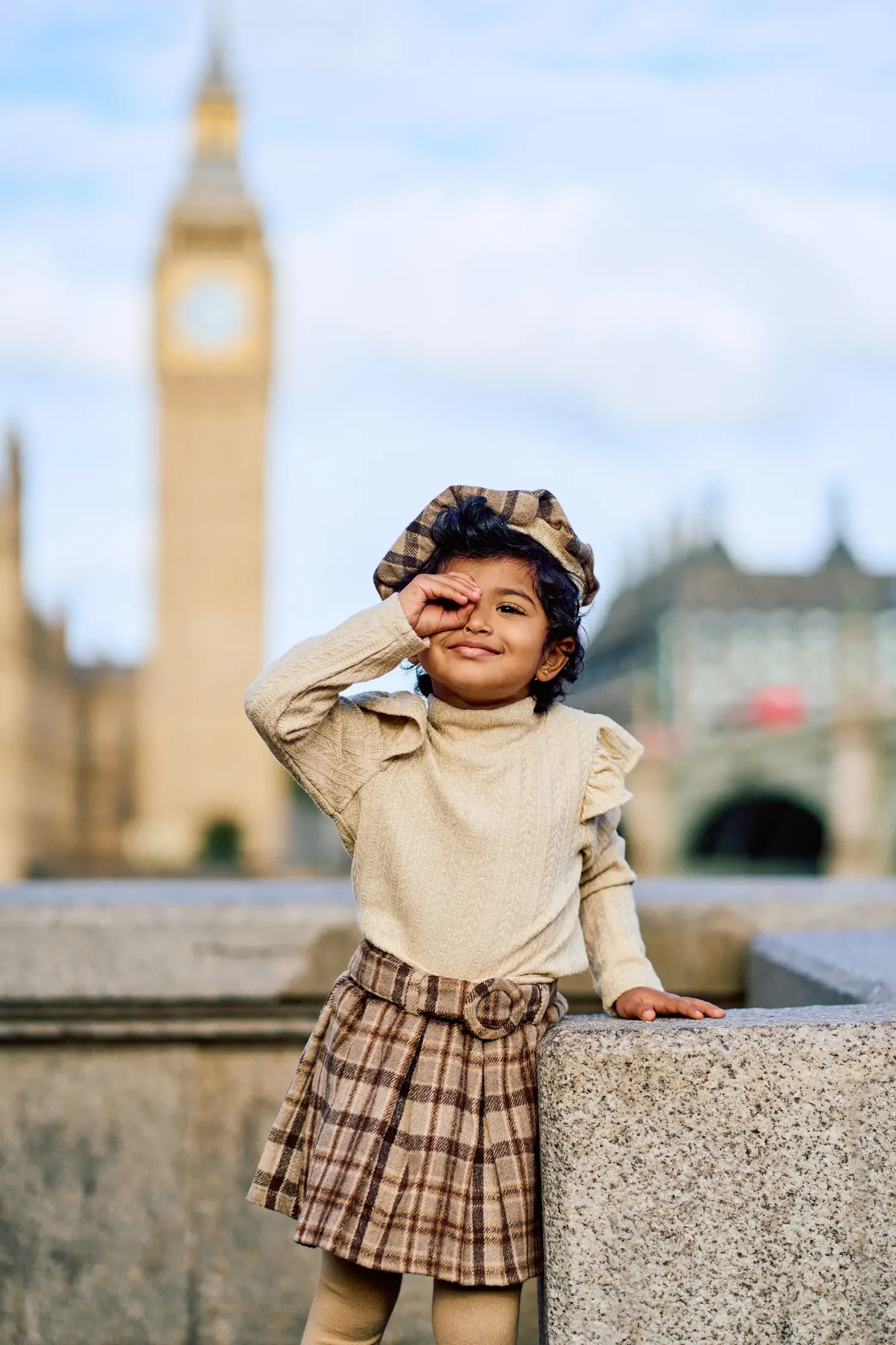 Toddler girl in a beret playing peekaboo on Westminster Bridge, Big Ben behind
