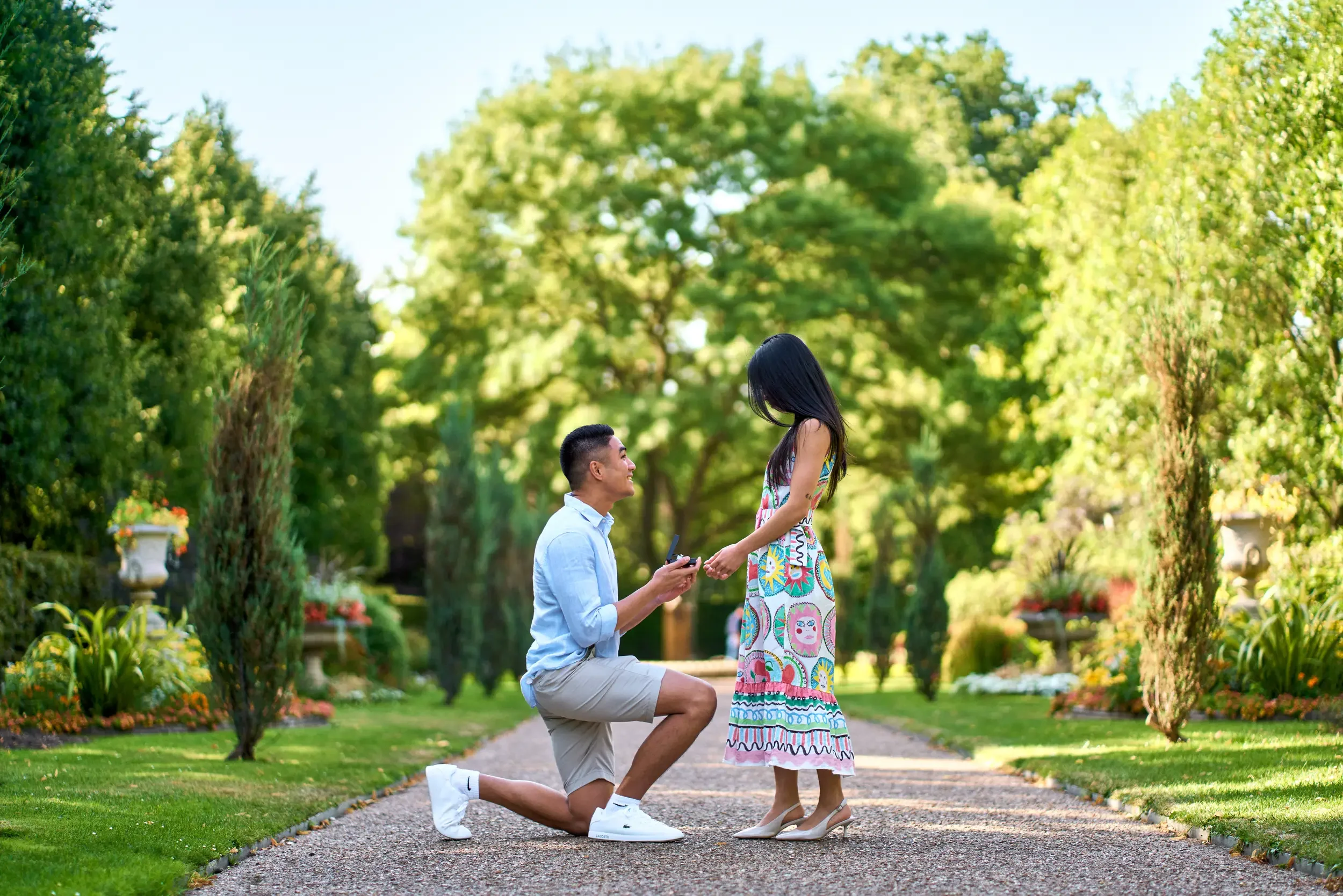 Man down on one knee proposing on a garden path surrounded by lush greenery in Regent's Park, London