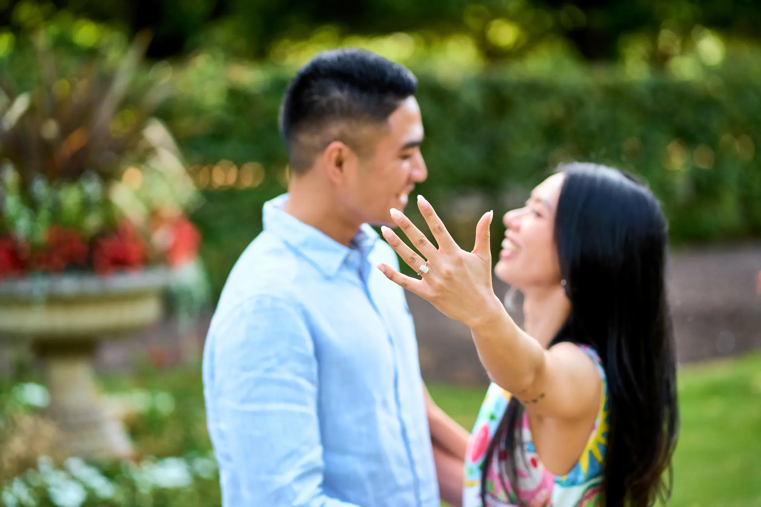 Newly engaged woman showing off her engagement ring while laughing with her partner in Regent's Park, London
