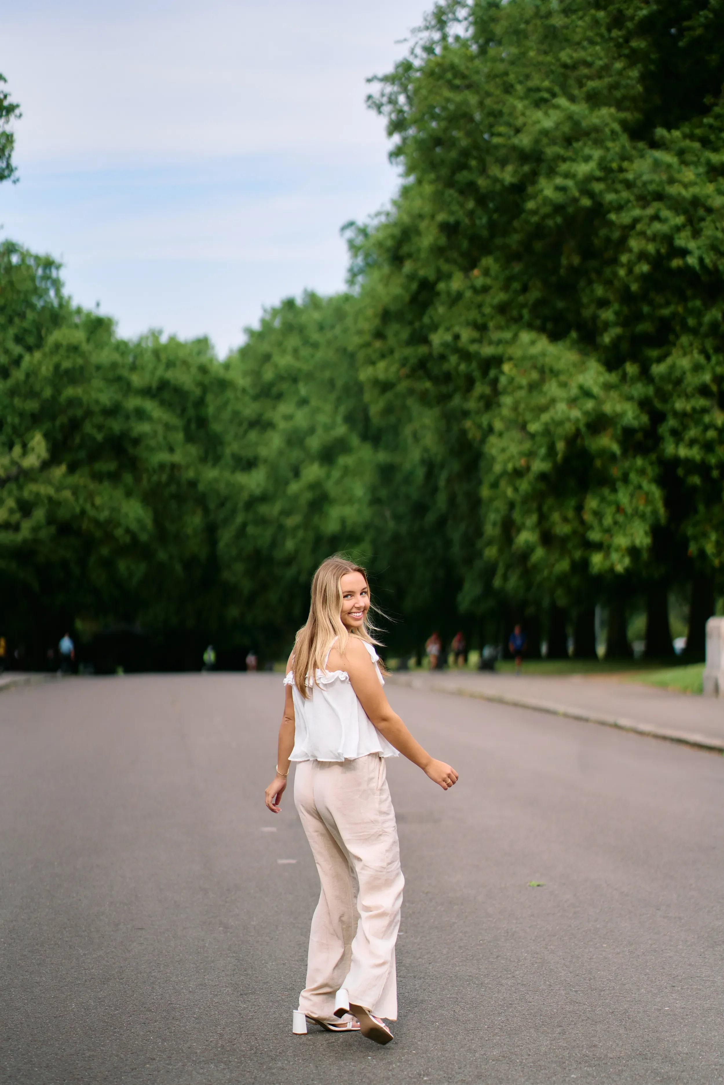 High school senior standing in front of an ornate black door with olive trees and decorative stonework in Kensington, London