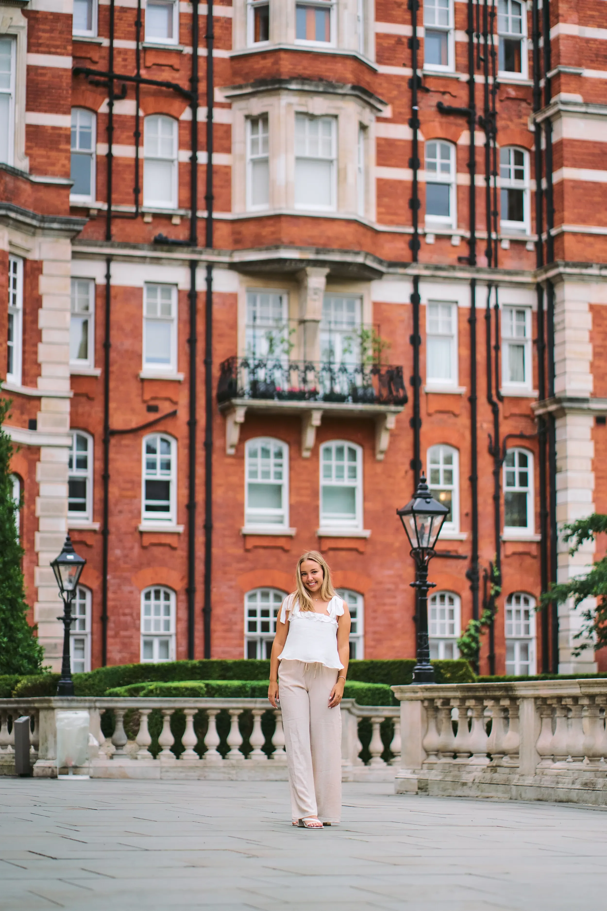 Smiling high school senior leaning against a red brick wall during a portrait session in Kensington, London