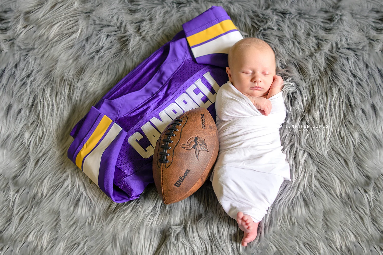 Sammamish in-home photo session of newborn with football and jersey.