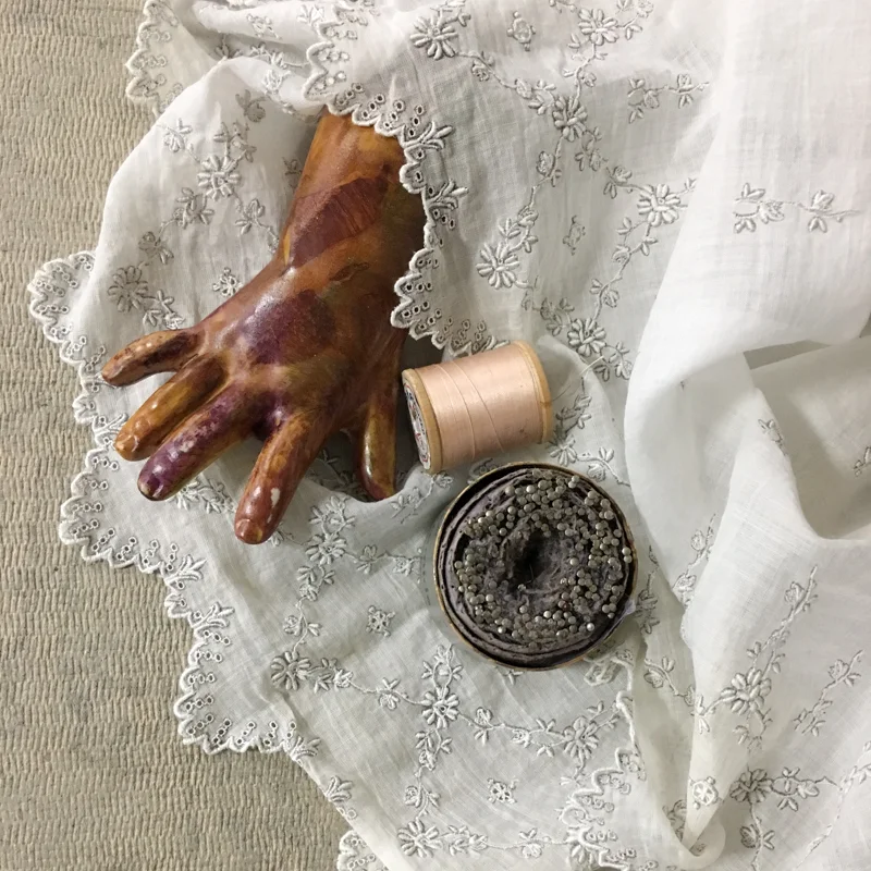 Ceramic doll hand, thread, pins, fabric and homasote; installation variable
