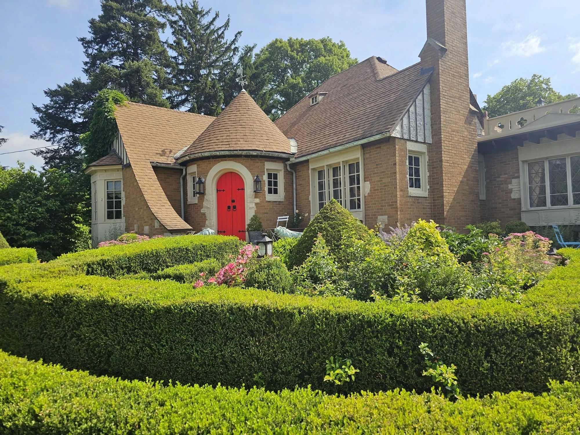 Weber House with its red front door and turret behind the boxwood knot garden, a ceremony backdrop
