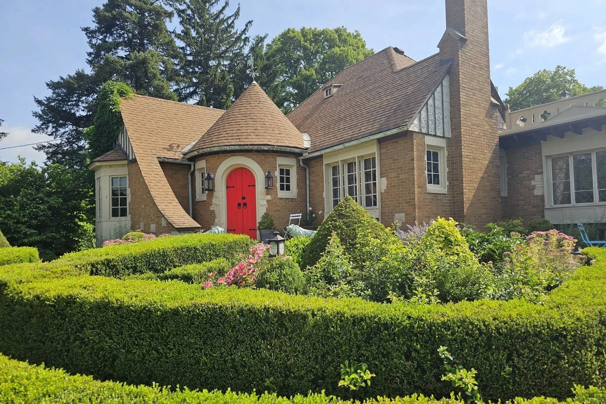 Weber House with its red front door and turret behind the boxwood knot garden, a ceremony backdrop
