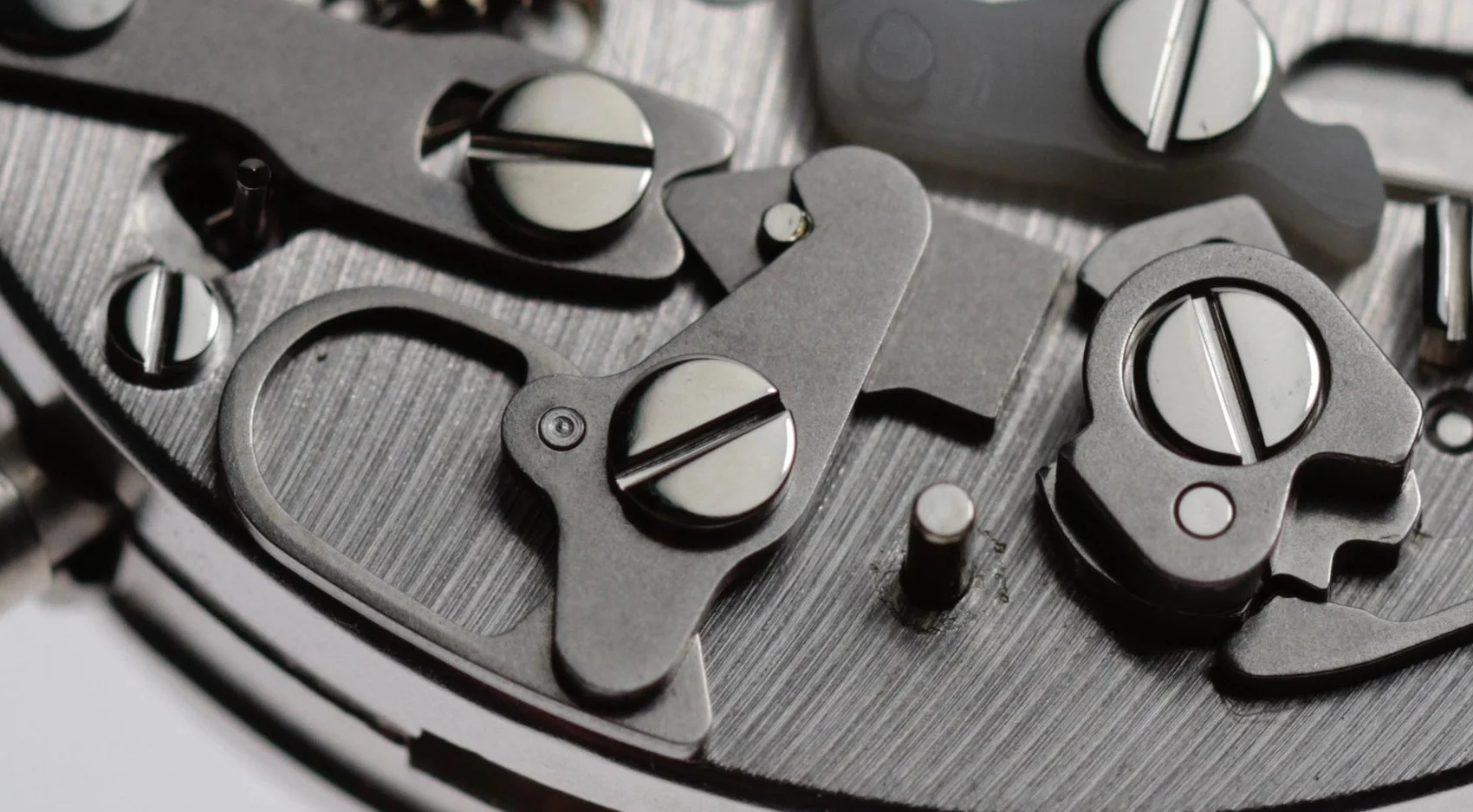 The lever in the centre of the image holds down the piece underneath it which in-turn pushes against the cam system. The central lever pushes this pieces to the left to reset each time the pusher on the outside of the case is manually activated.
