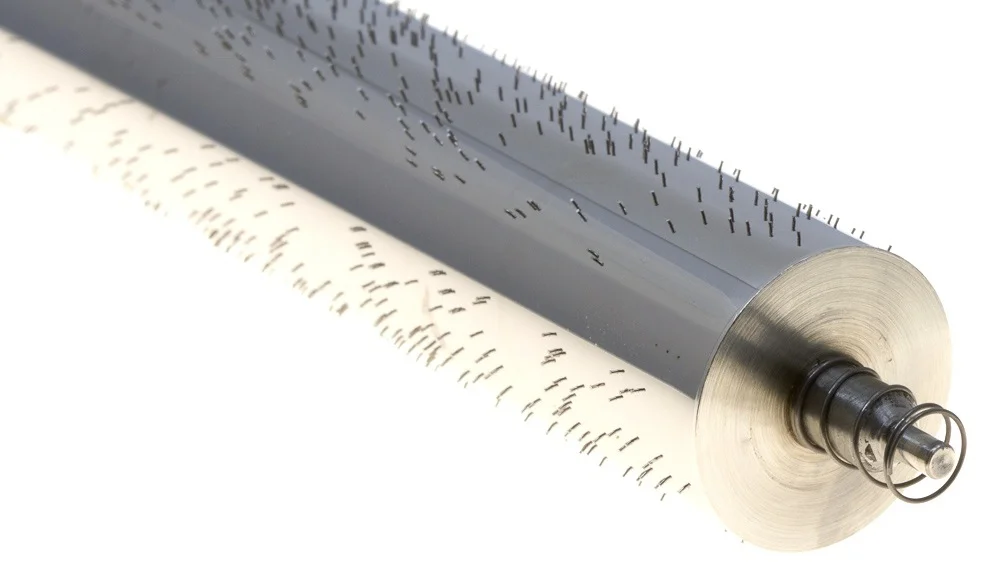 The spring pushes the cylinder towards the opposite end, removing all end shake but allowing the three toothed cam to adjust the position of the cylinder in relation to the 3 different melodies.