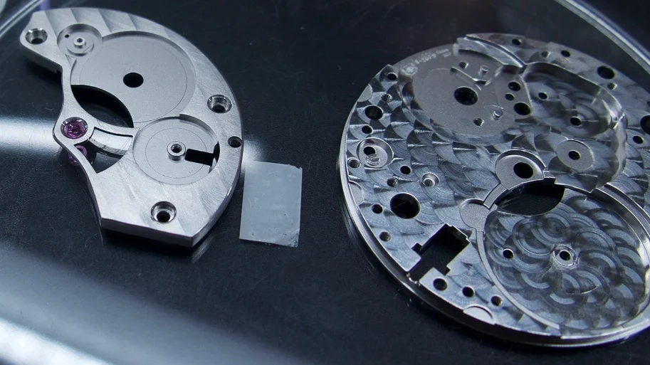 The barrel bridge has been partially skelletonized to high-light the centre wheel, the bridge form is altered and angled. The surface has a Geneva stripe decoration. The mainplate spotted (pearlage).