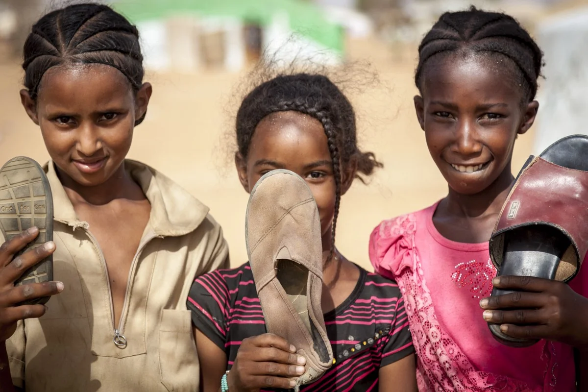 The kids showing me the things they play with, from old motorcycle tires to shoes which are used to replace balls in a game very like Botchi.