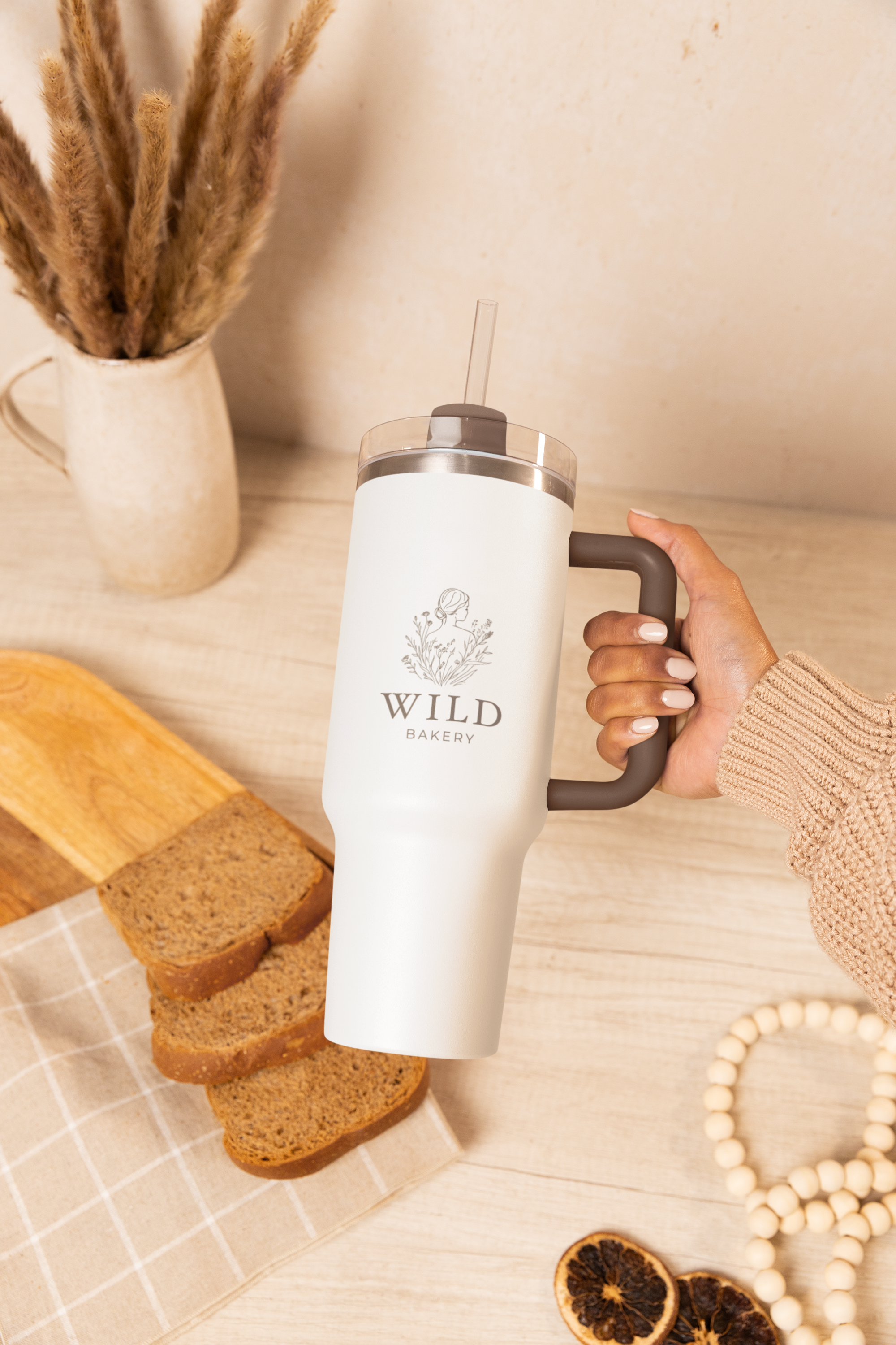 stanley-tumbler-mockup-featuring-a-woman-s-hand-against-a-table-with-bread-slices-m54068.png