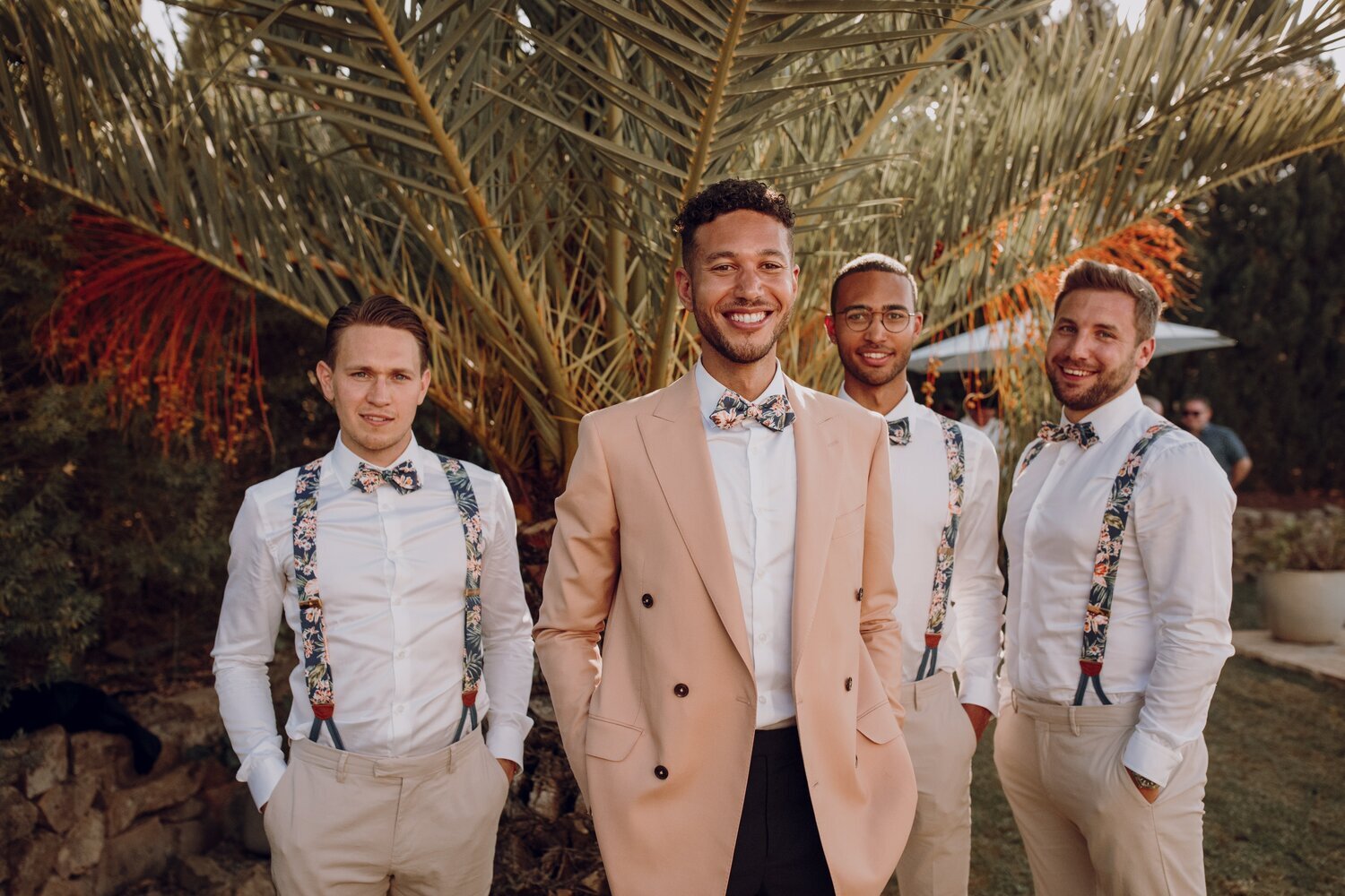 Groom wearing bespoke floral bow tie and groomsmen in tropical floral wedding braces and bow ties