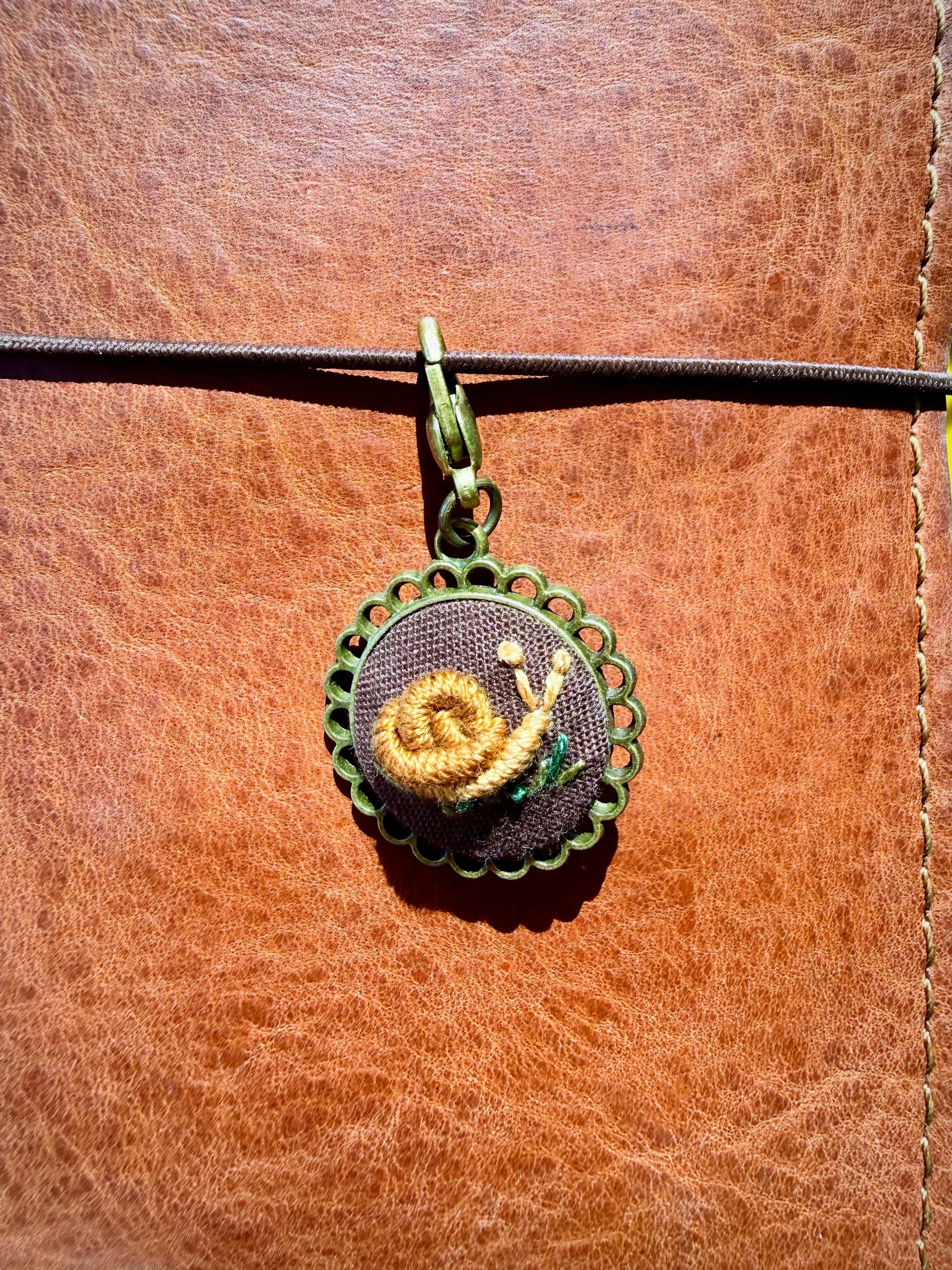 The cutest journal charm from @poppystitch as a beautiful reminder to slow down and notice everything around you. 🐌 

#writingmindset #snail #poppystitchstudio #embroidery #journal