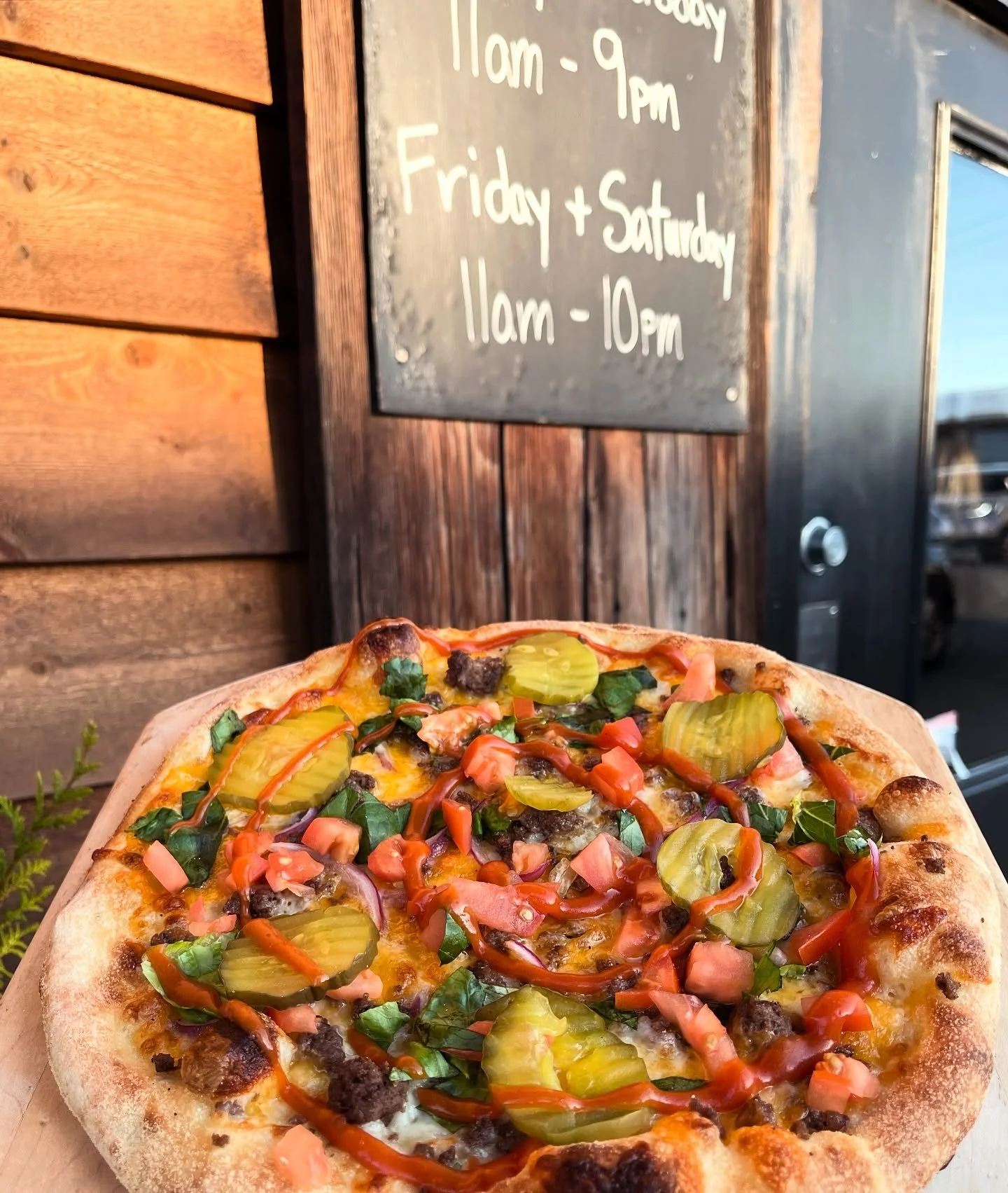 🍔 + 🍕 = Cheeseburger Pizza! Jack Mountain Meat&rsquo;s ground beef with a blend of cheddar &amp; mozzarella cheeses, baked to perfection and topped with lettuce, diced tomatoes, red onion, and dill pickle chips. Finished with our house made burger 