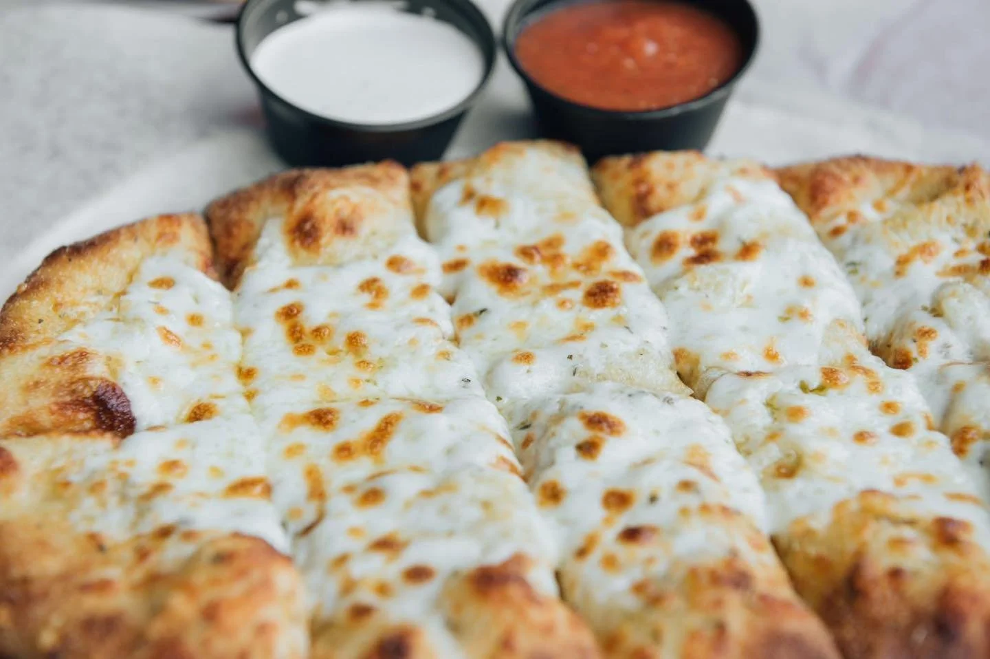 Our cheesy bread is one of your favorites! House made Italian herb bread with melted mozzarella served with marinara &amp; ranch dipping sauces. Perfect for sharing!