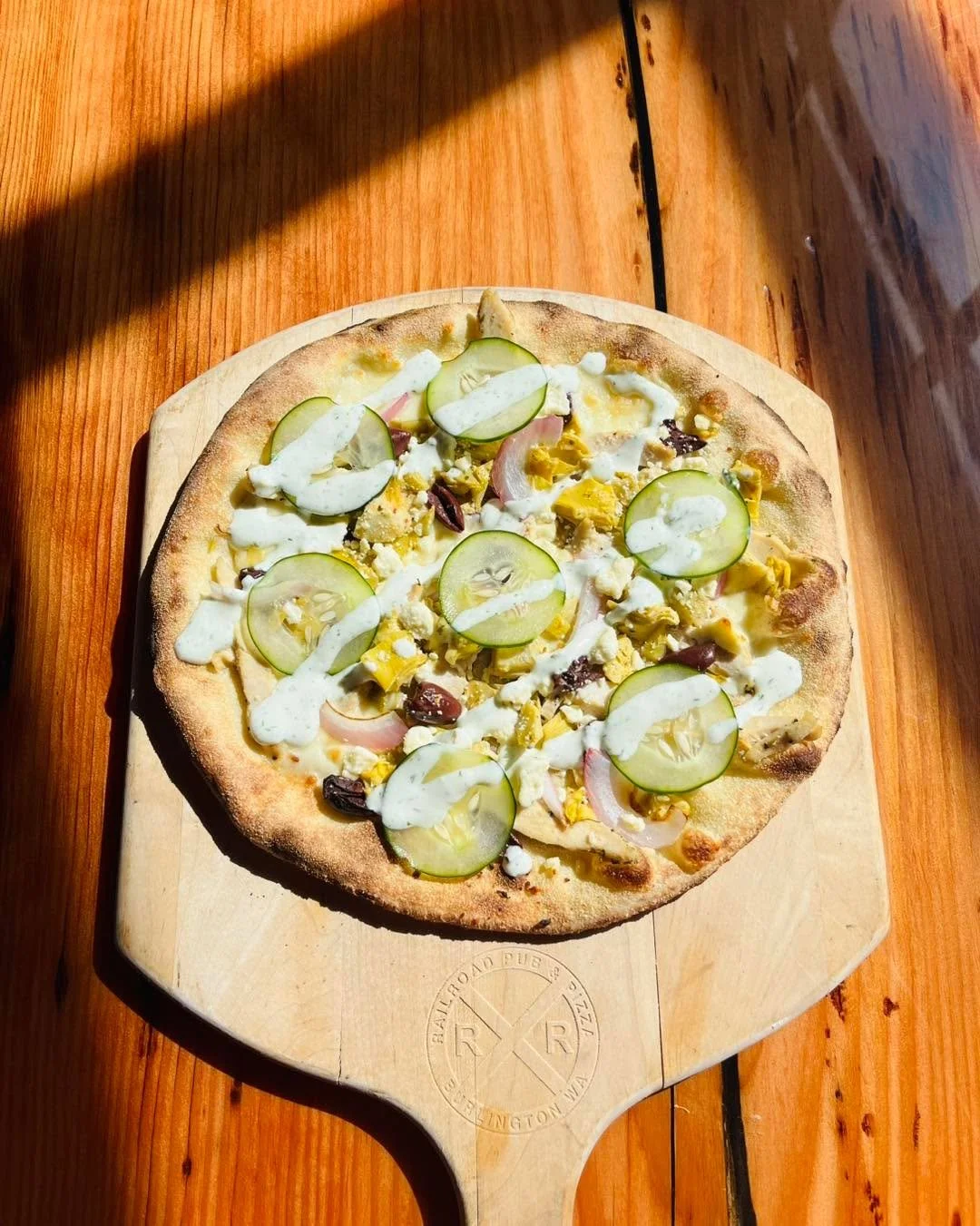 Introducing Greek Chicken Pizza&mdash;Fresh mozzarella, chicken, artichoke hearts, red onion, Kalamata olives and feta cheese! Topped with thinly sliced cucumber and our house made tzatziki sauce. Available on special for a couple of weeks, come on i