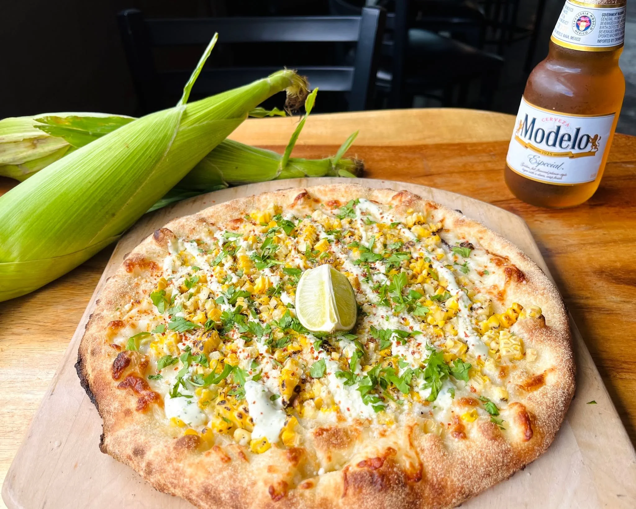 Our Elote Pizza special is made with fresh, locally sourced roasted corn from @schuhfarms and shredded mozzarella, topped with Cotija cheese, cilantro, lime, Taj&iacute;n, and Mexican crema. 🌽🔥🧀
