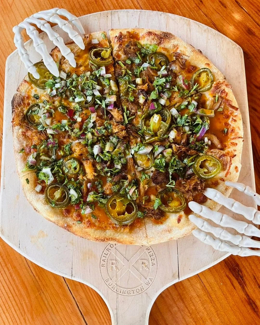 Spice up your Sunday with our Spicy Caroline pizza special! Carolina BBQ sauce, a cheddar &amp; mozzarella cheese blend, jalape&ntilde;os, and smoked pork from Train Wreck Bar &amp; Grill, topped with red onion and cilantro.