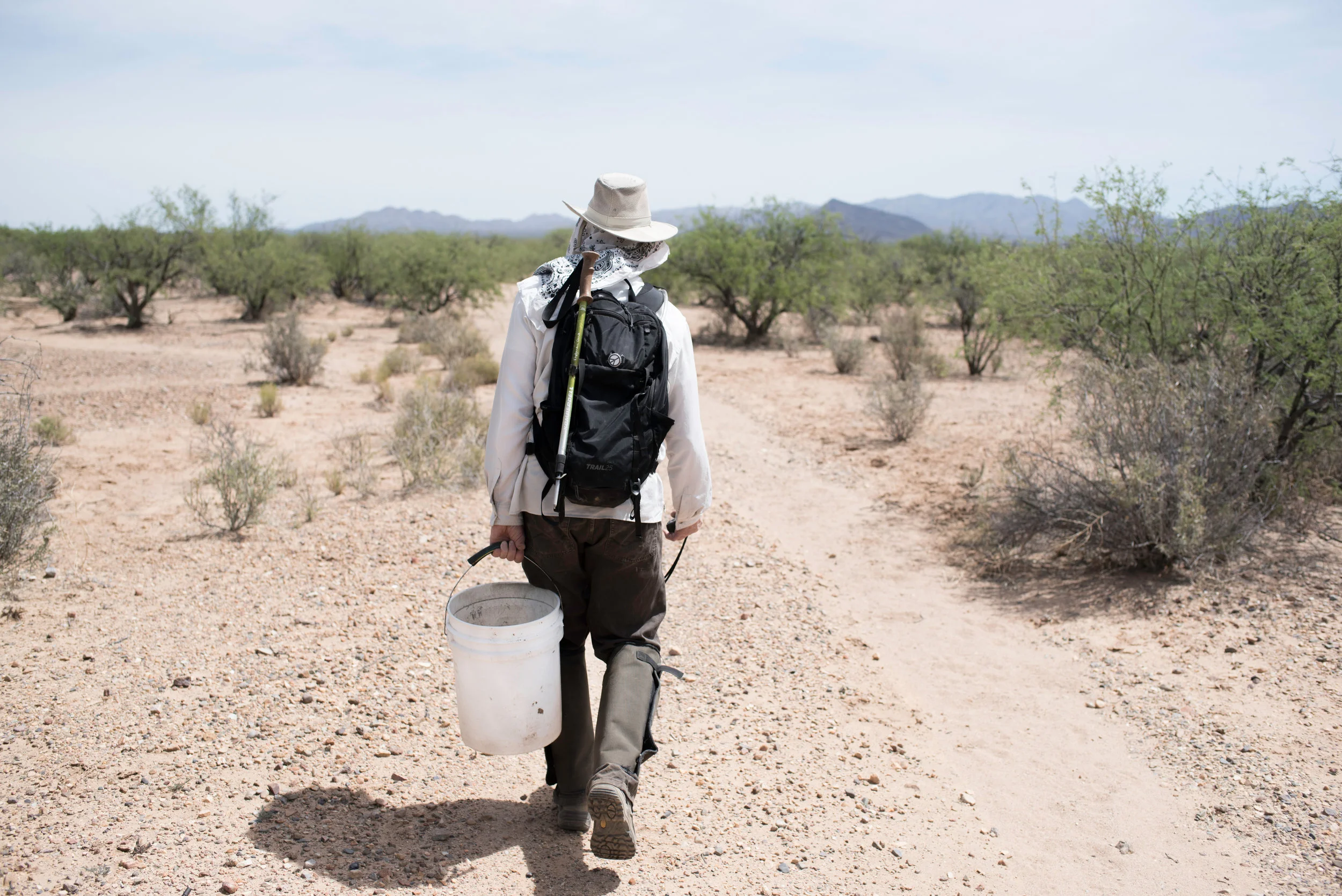 One of Alvaro's volunteers carries water for miles towards a new grave site .jpg