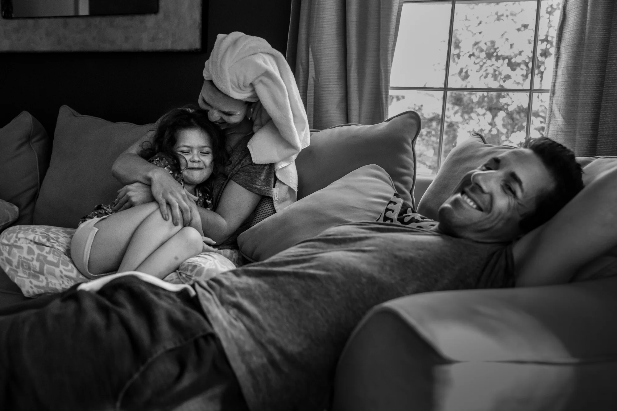 Mother and daughter snuggle while father smiles
