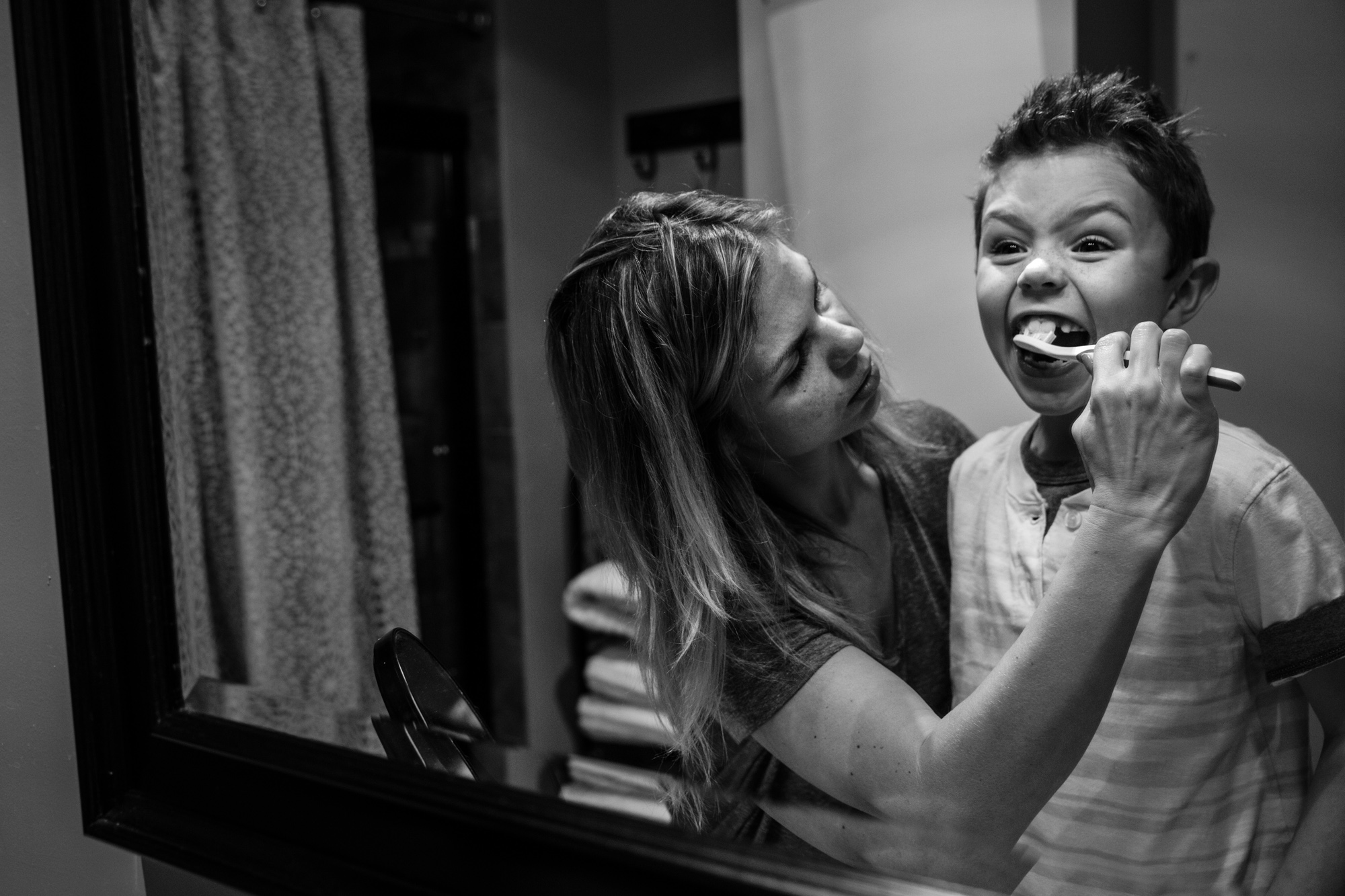 Woman brushes boy's teeth