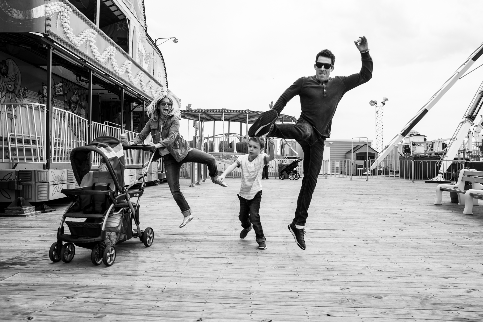 Family does bell kicks while pushing stroller at the boardwalk