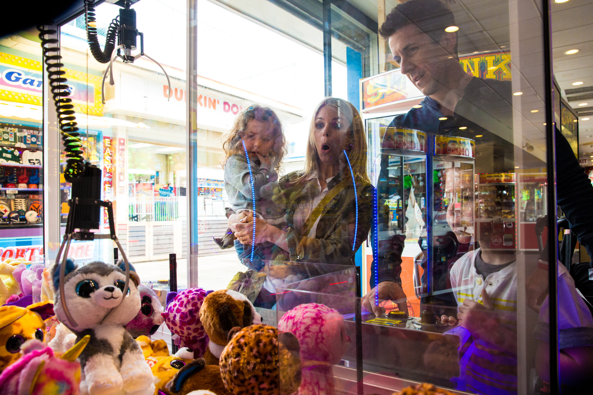 Claw grabs prize at the arcade while family watches in suspense