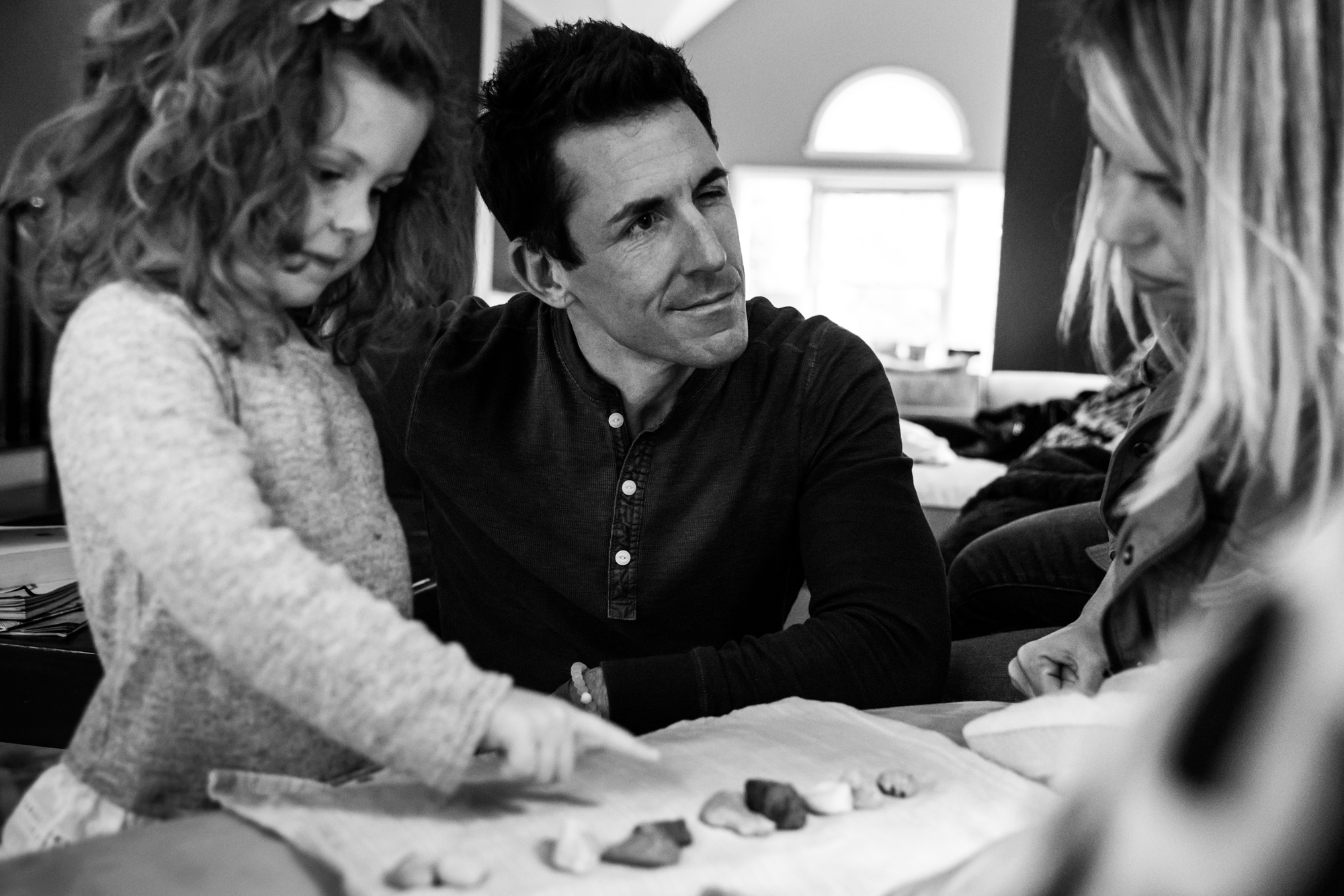 Man winks at his wife while daughter points at rocks