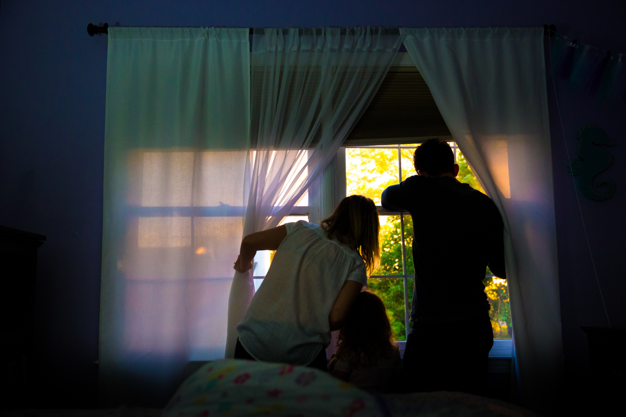 Family looks out the window at sunset sky