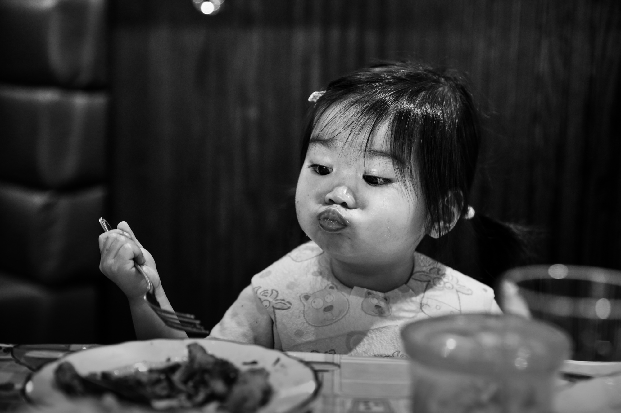 Girl puffs her cheeks out while looking at her food on a plate