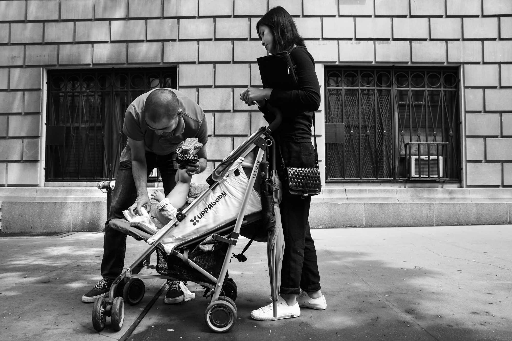 Man changes diaper on the sidewalk in a stroller