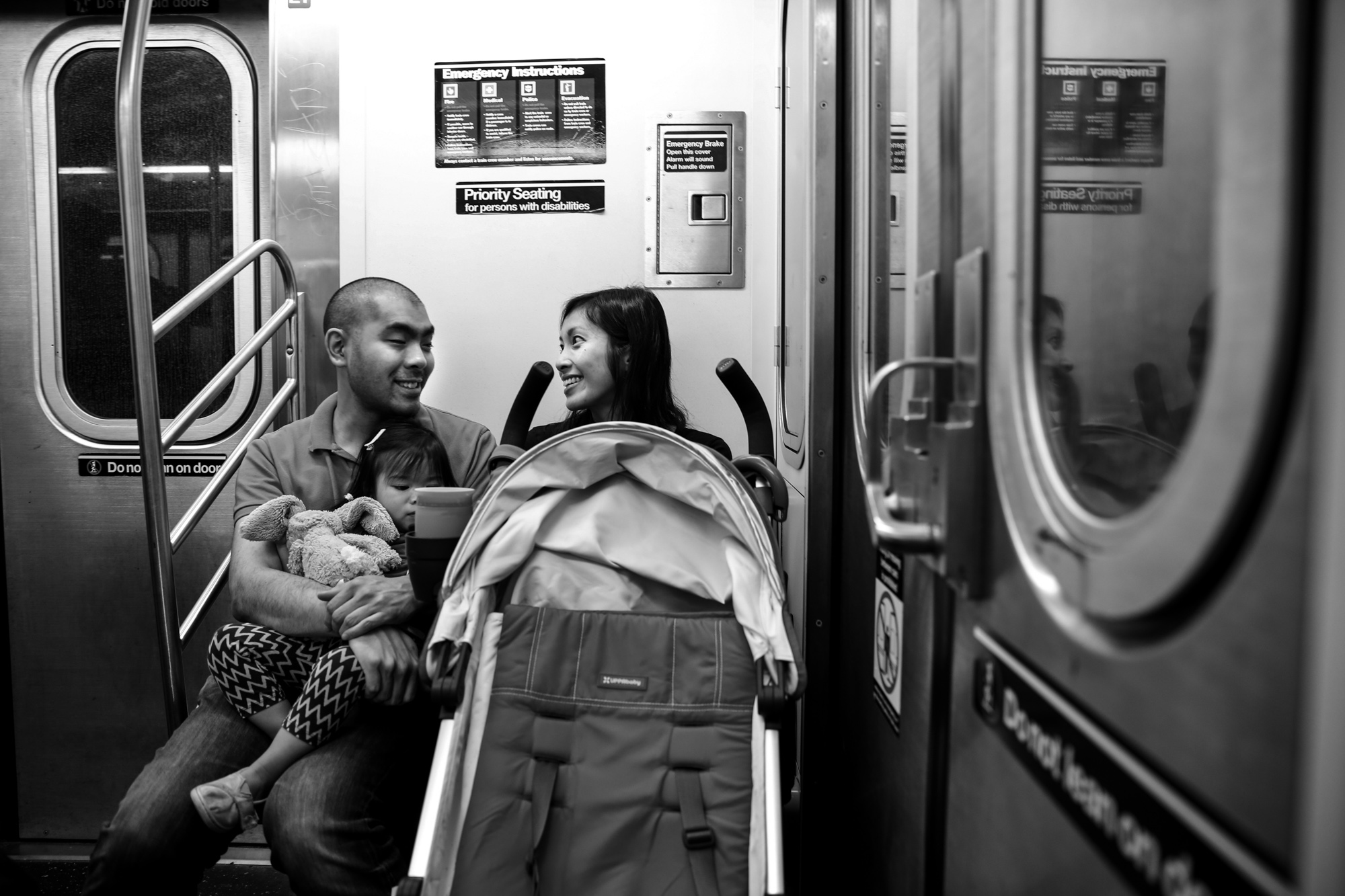 Man, woman and child ride the subway with their stroller