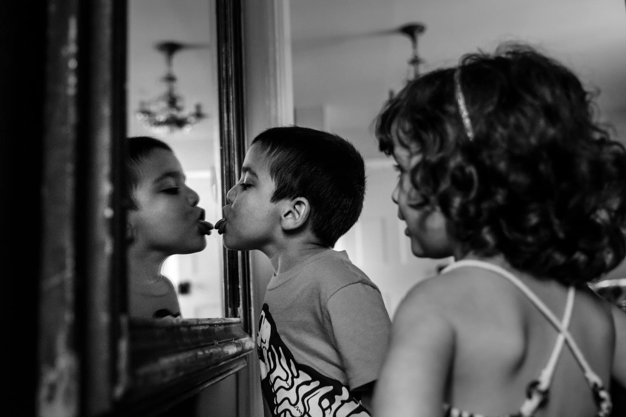 Boy licks mirror while girl watches