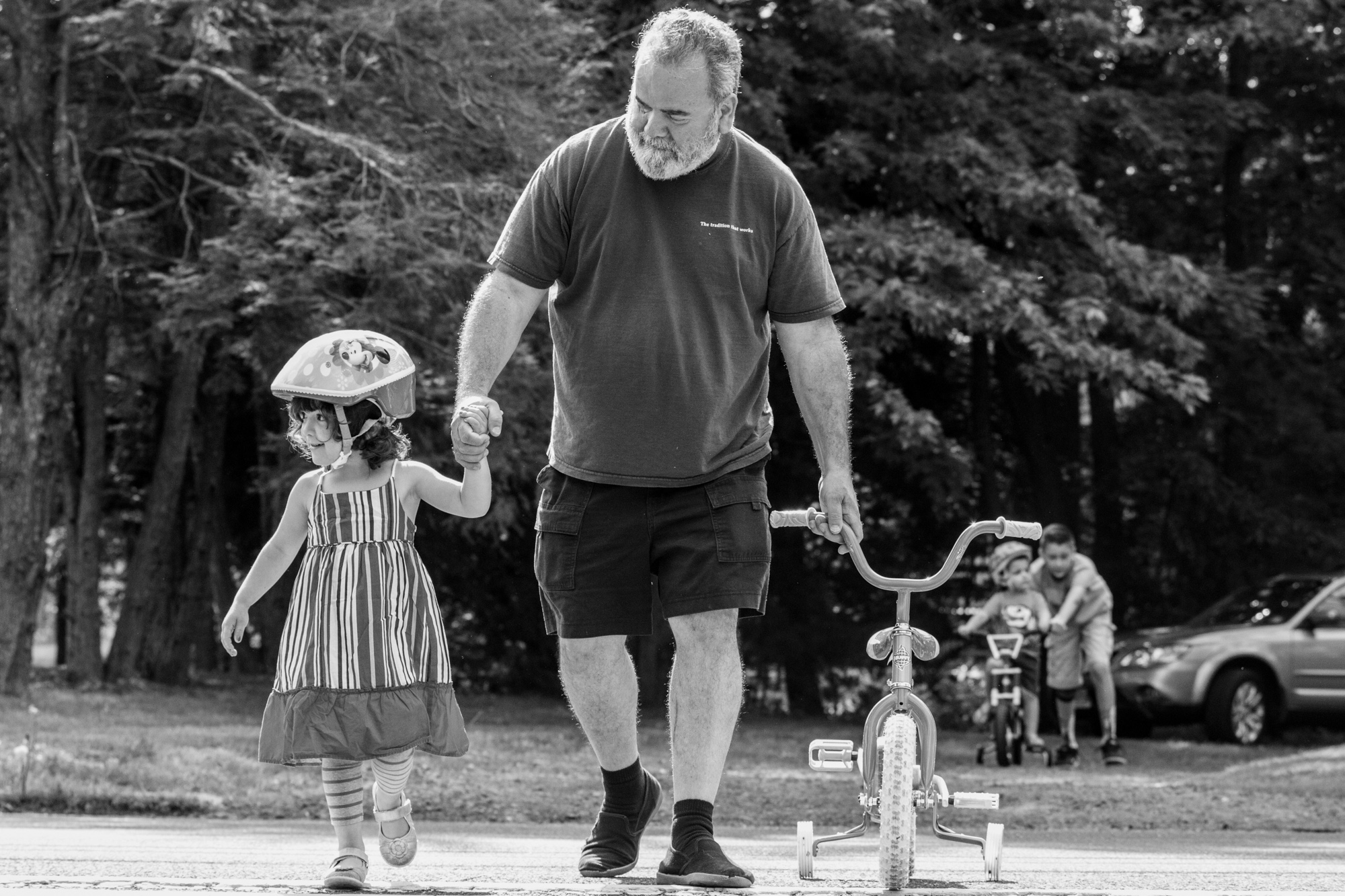 Girl with helmet holds hand with man holding a bike