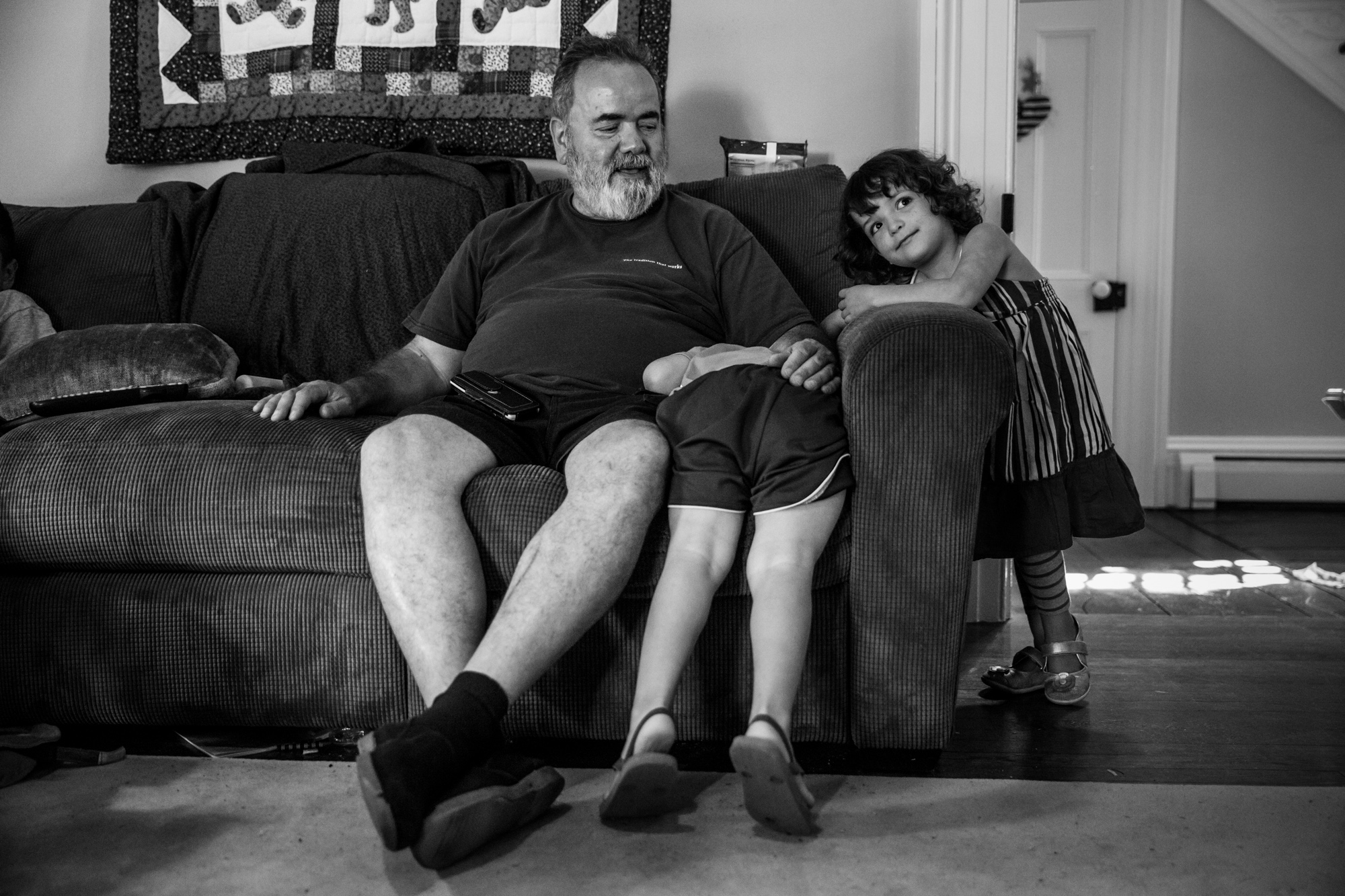 Man sits on couch while boy and girl lean on couch