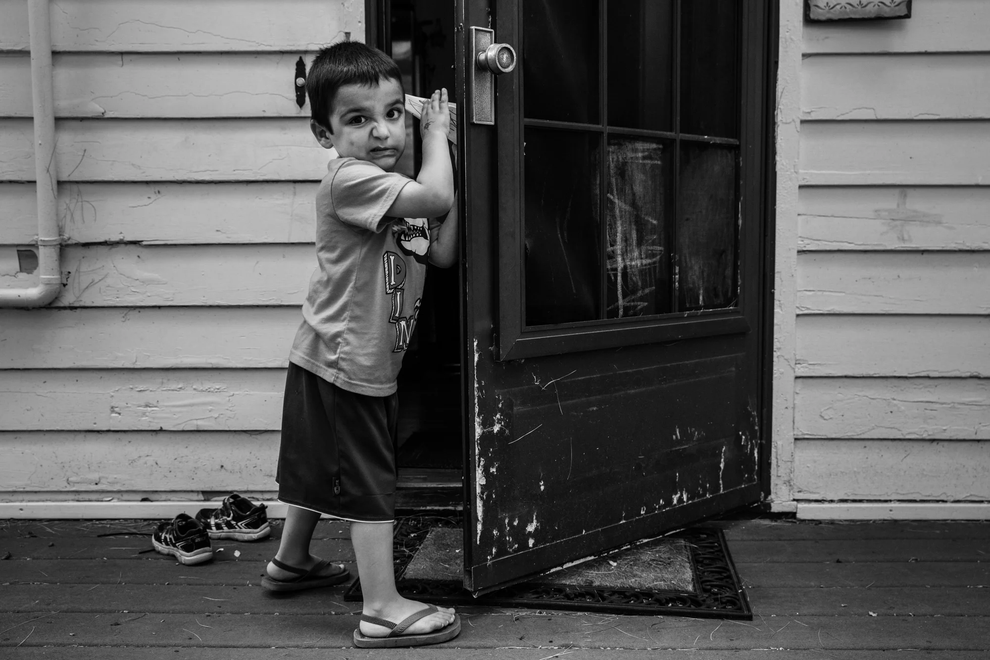 Boy grimaces while holding open a door