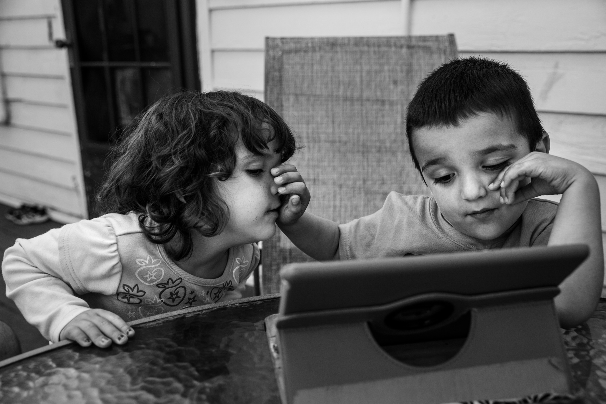 Boy pushes girl's face away while watching iPad