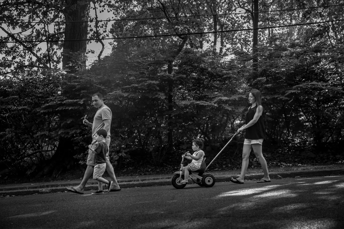 A family of four walk down a street while eating ice pops