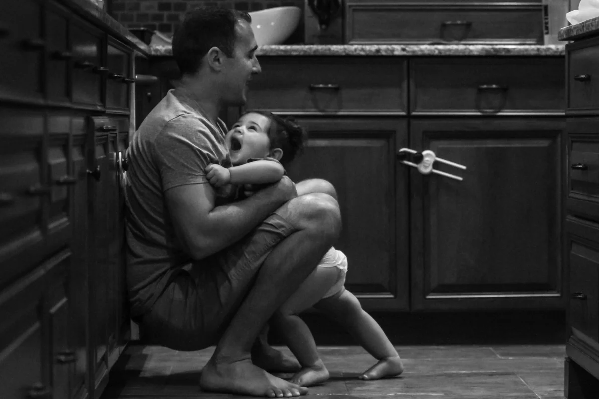 Girl runs into father squatting on the floor and smiles